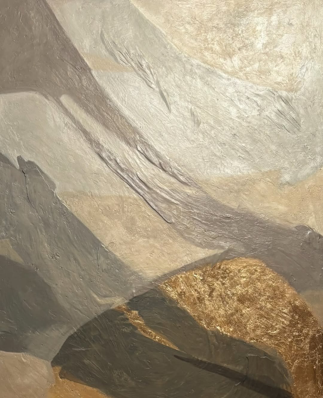 Close-up of a textured painting with layered, rough, and smooth surfaces in gray and tan/brown tones.