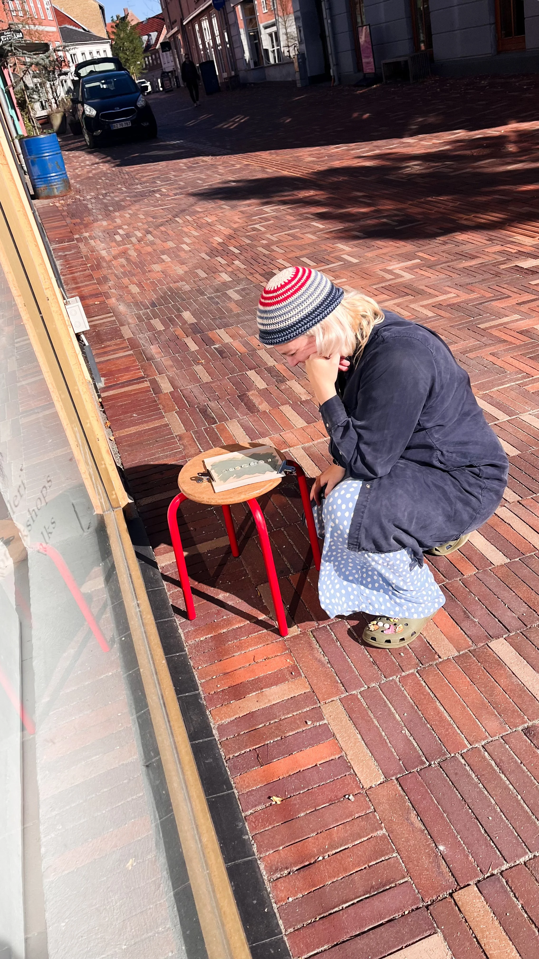 Kvinde sidder på hug i solen og kigger på sit cyanotypi under en workshop