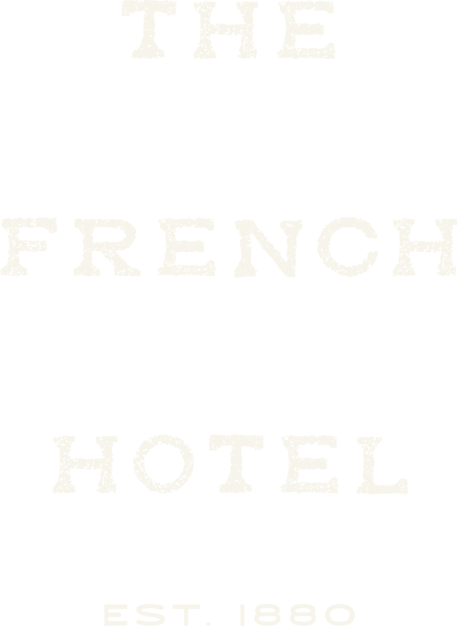 Vintage sign reading "The French Hotel, Est. 1880" in white distressed lettering on a black background.