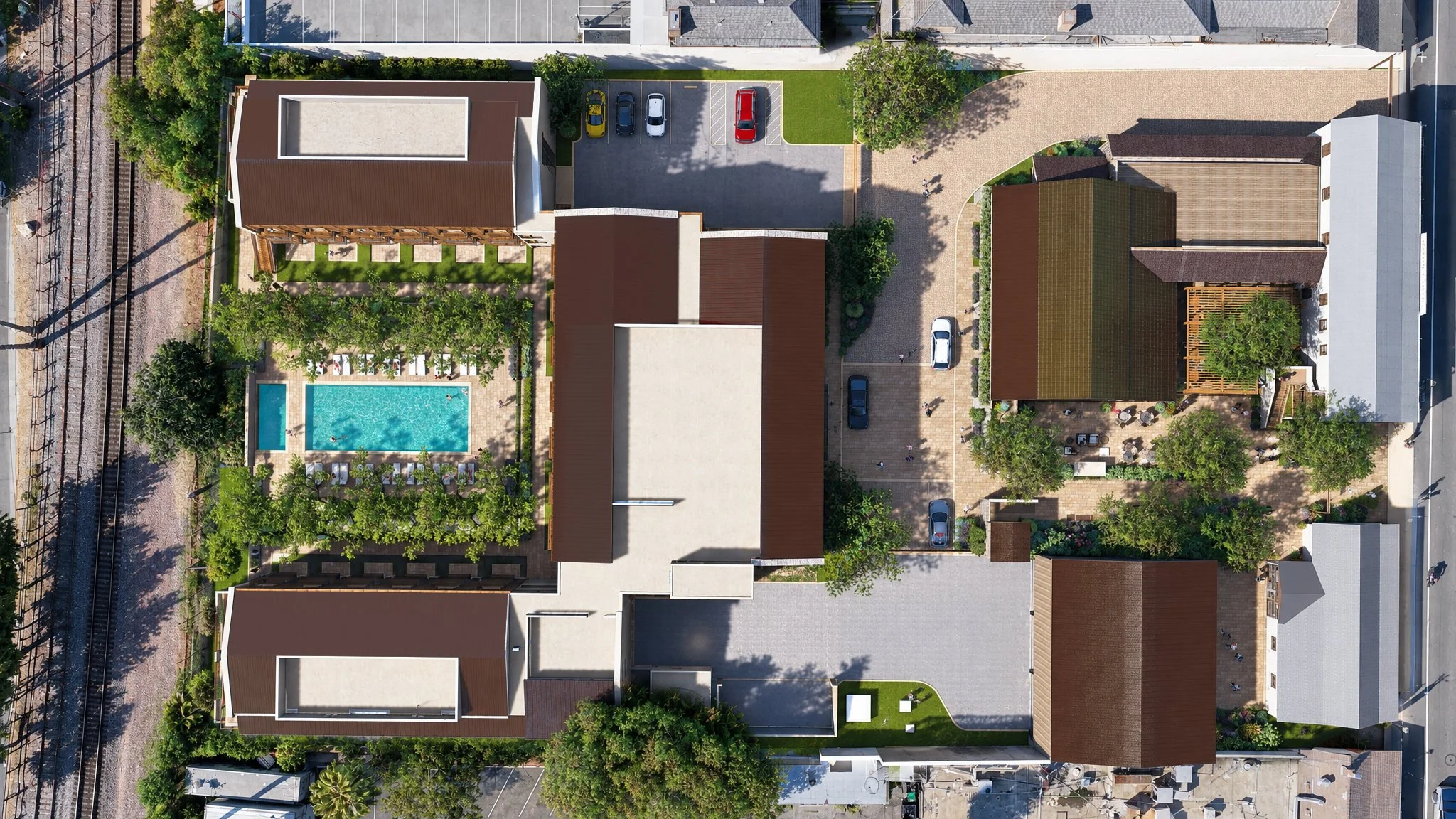 An aerial view of The French Hotel site with a swimming pool, parking lot with cars, green trees, and surrounding buildings.
