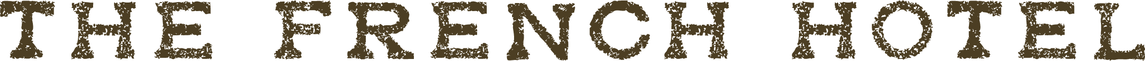 Close-up of a worn, vintage sign with the words "The French Hotel" in black, textured lettering on a dark, uneven surface.
