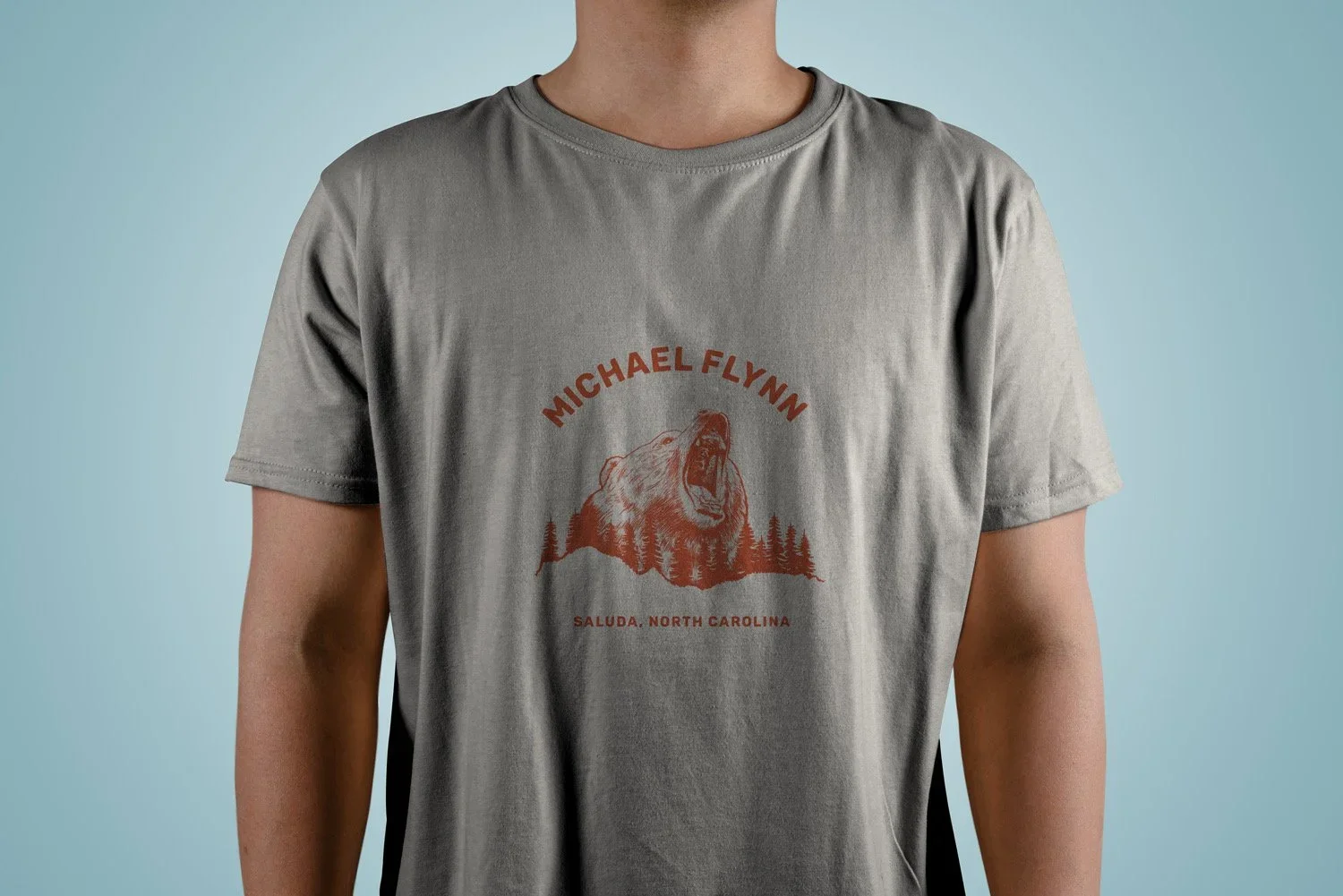 Gray T-shirt featuring a roaring bear graphic, the text “Michael Flynn” and “Saluda, North Carolina.”