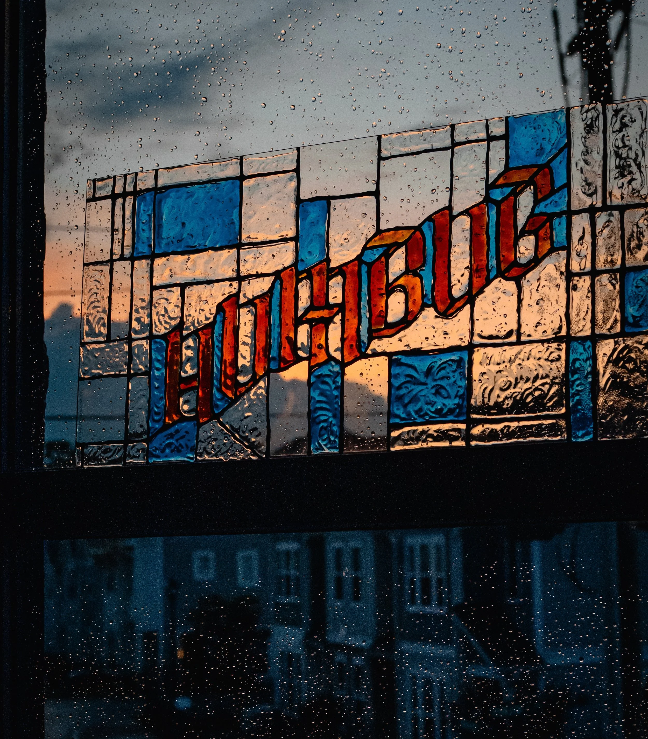 Rain-speckled stained-glass window with colorful blue, orange, and gray geometric panels