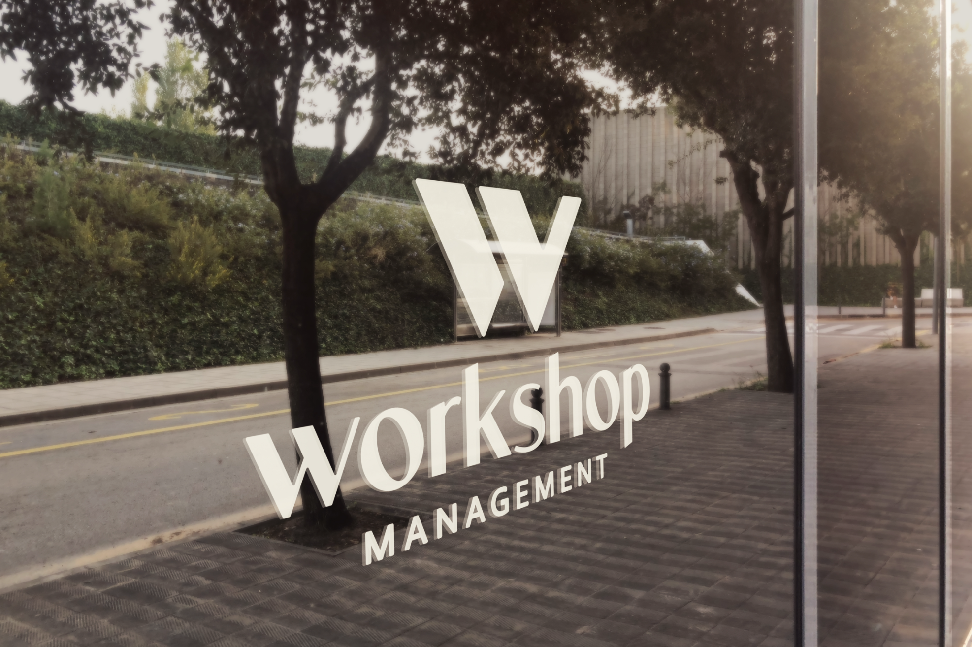 Window graphic reading “W Workshop Management” on a tree-lined urban street.