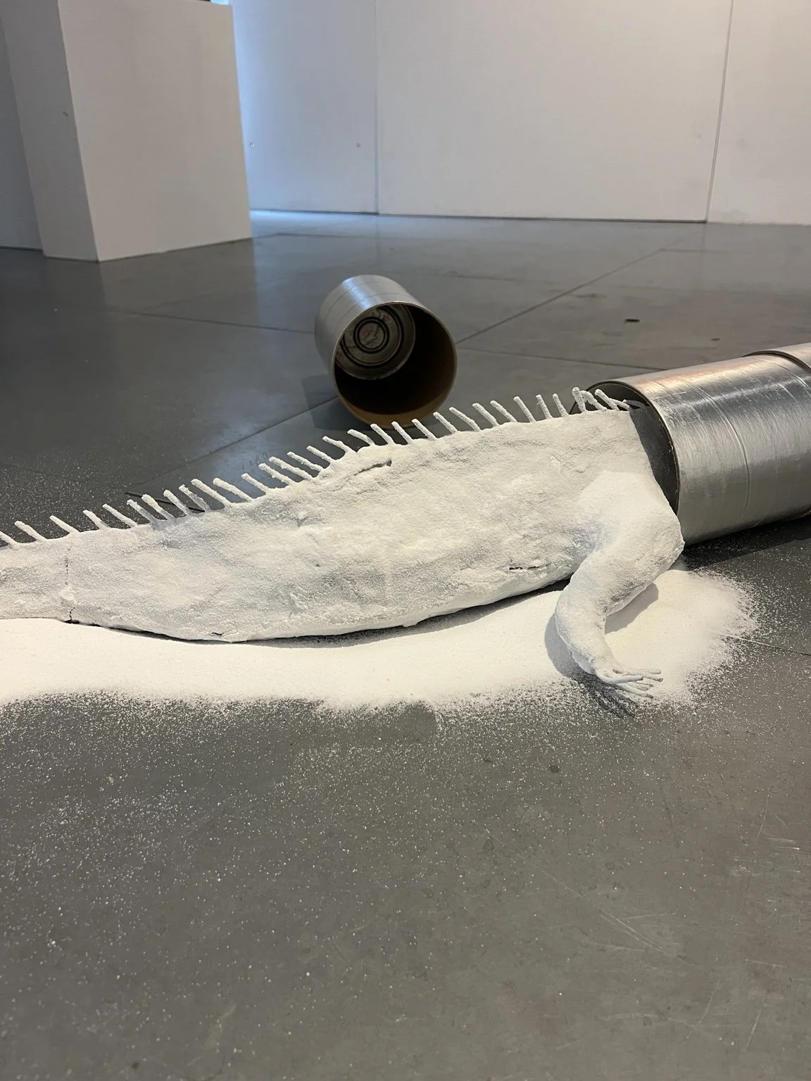 Detail view of Anastasia Belinskaya's No Place To Hide (2026) in Commencement / Commandment at Prokofiev Studio, London, showing a reclaimed British Antarctic Survey ice-core storage cylinder with sculpted clay and white silica sand spilling onto the