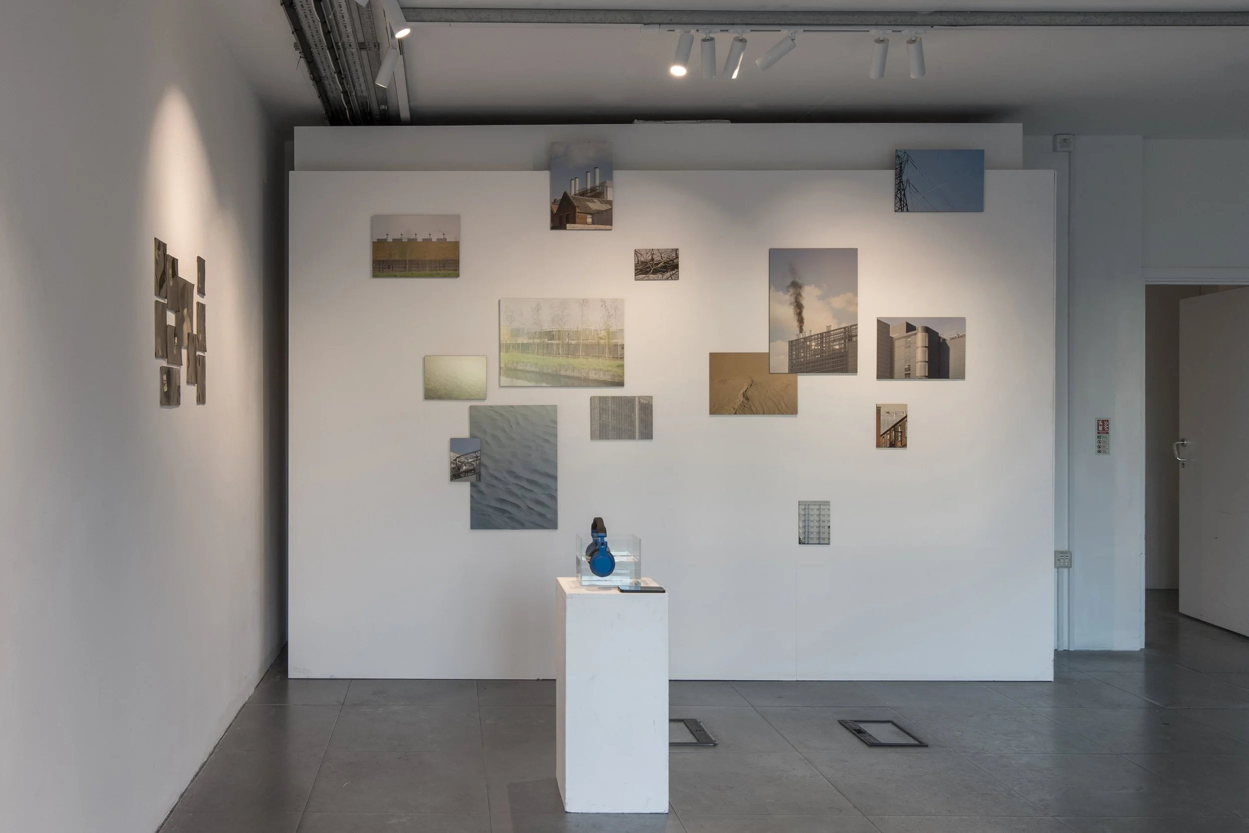 Installation view of Clouds That Never Rain (2026) by syntheticduo (Anastasia Belinskaya and Polina Kravchenko) in Commencement / Commandment at Prokofiev Studio, London. Photographs of industrial structures, landscapes and technological infrastructu