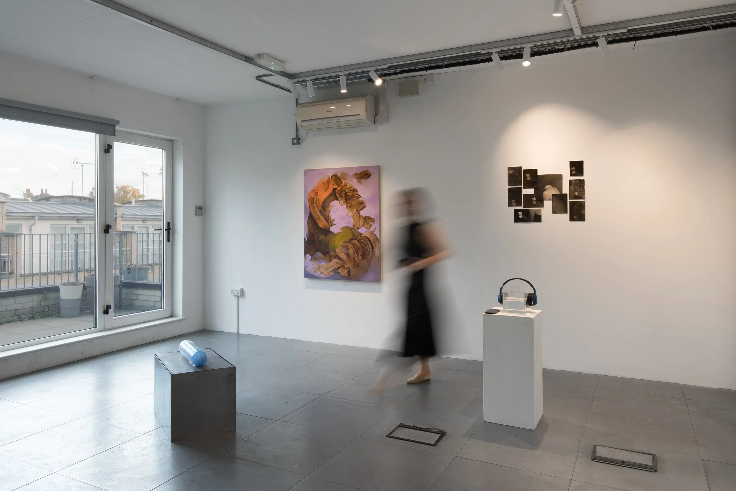 Installation view of Commencement / Commandment (2026) at Prokofiev Studio, London, featuring Anastasia Belinskaya's ice-based sculpture Slowest Wave (2026) on a metal plinth, Kika Sroka-Miller's painting Not drawn from nature (2026), and Gülce Tulça