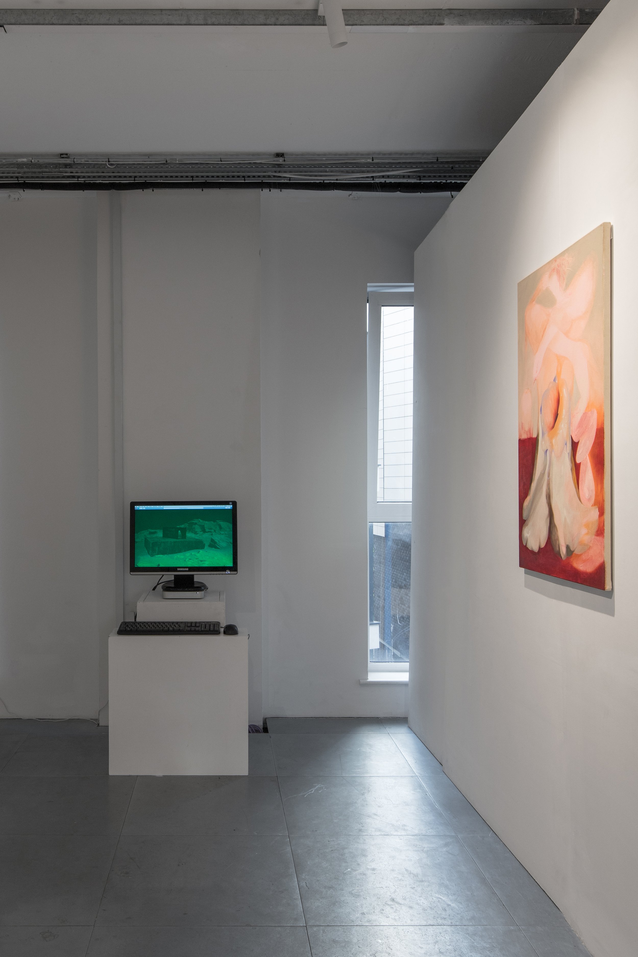 Installation view of Commencement / Commandment (2026) at Prokofiev Studio, London, showing Harry Payne's interactive digital work Find the Archive (2026) on a computer monitor at the end of the gallery, with Kika Sroka-Miller's painting You are free