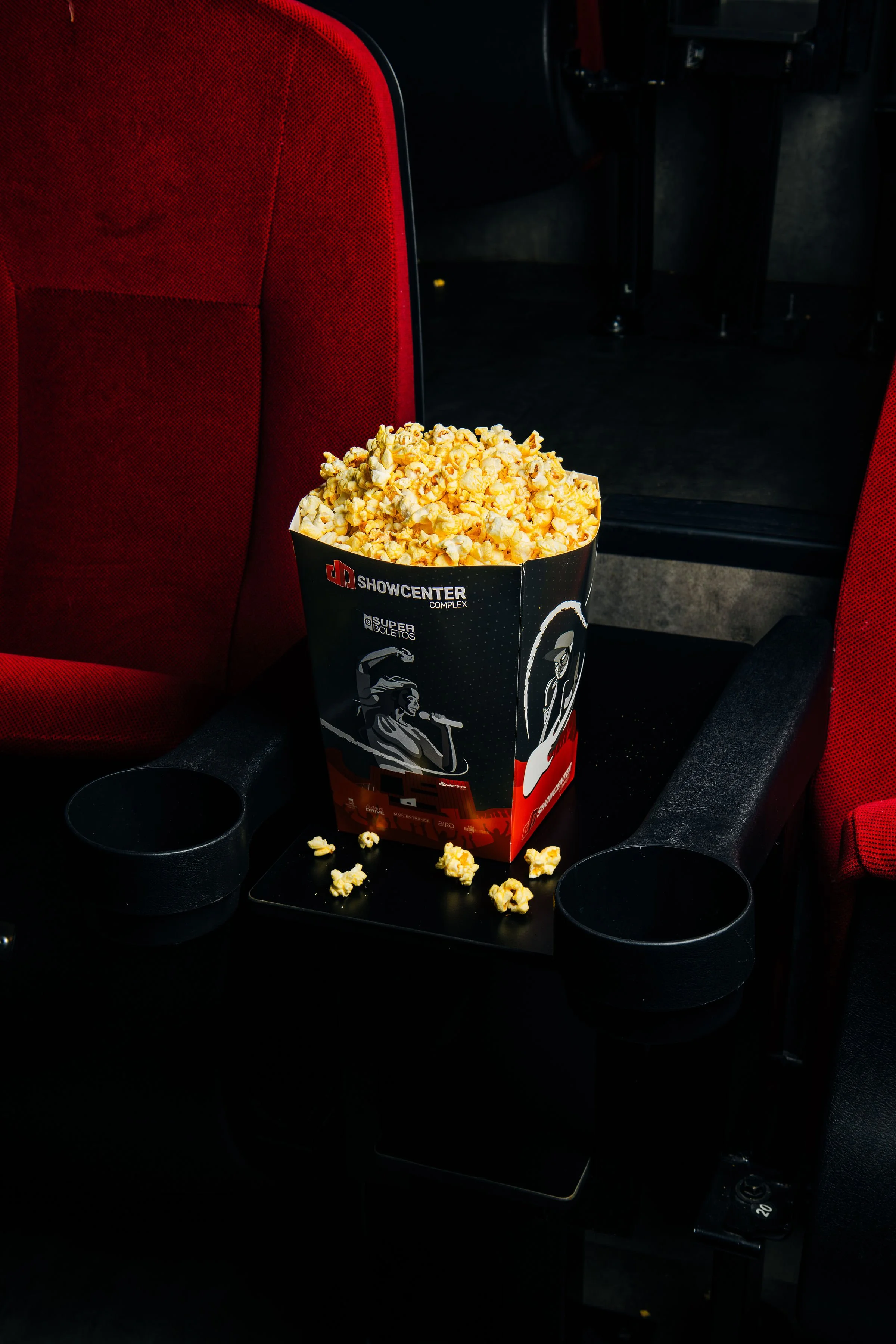 Palomitas colocadas junto a butacas rojas de cine.