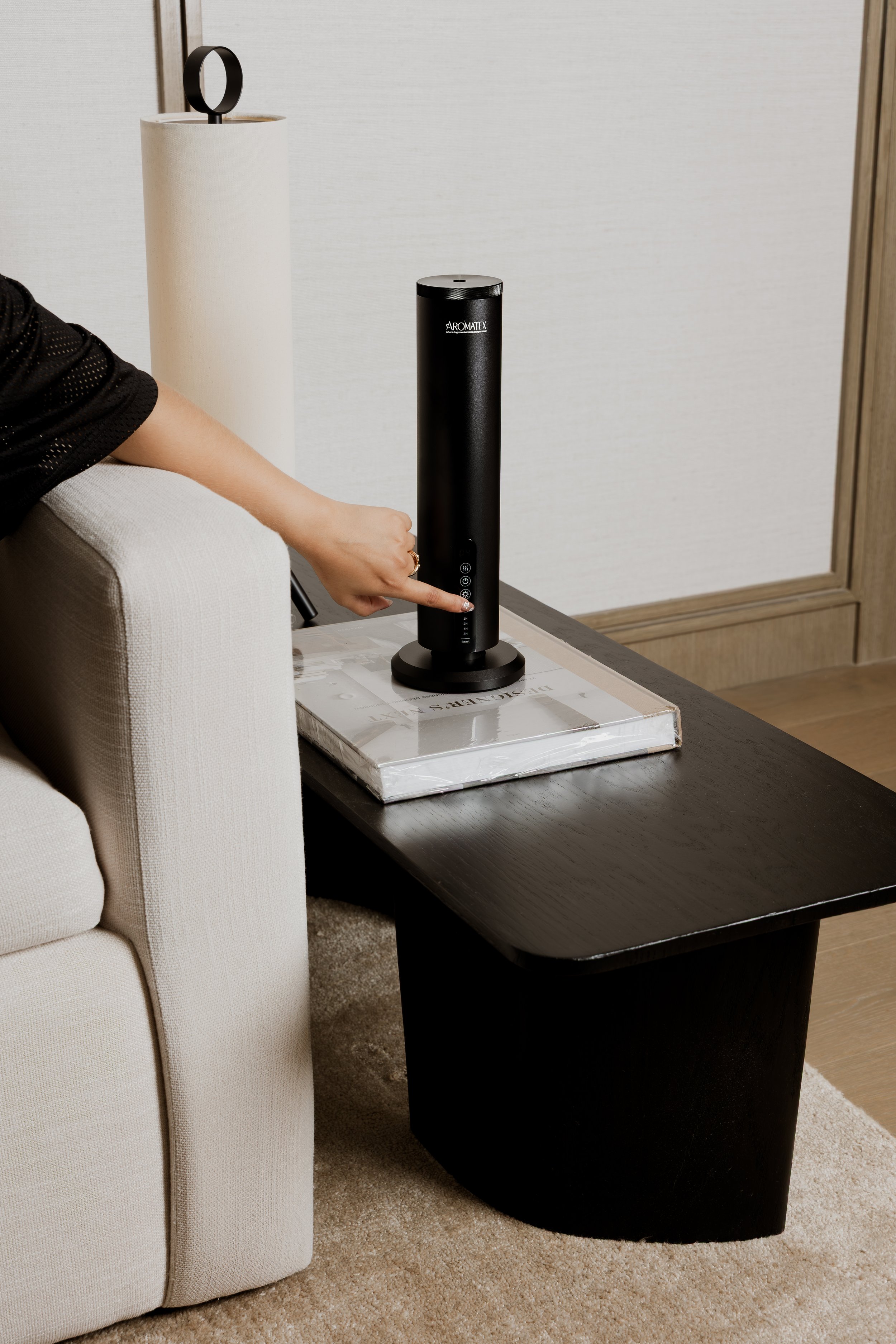 Persona usando un difusor Aromatex junto a un sofá.