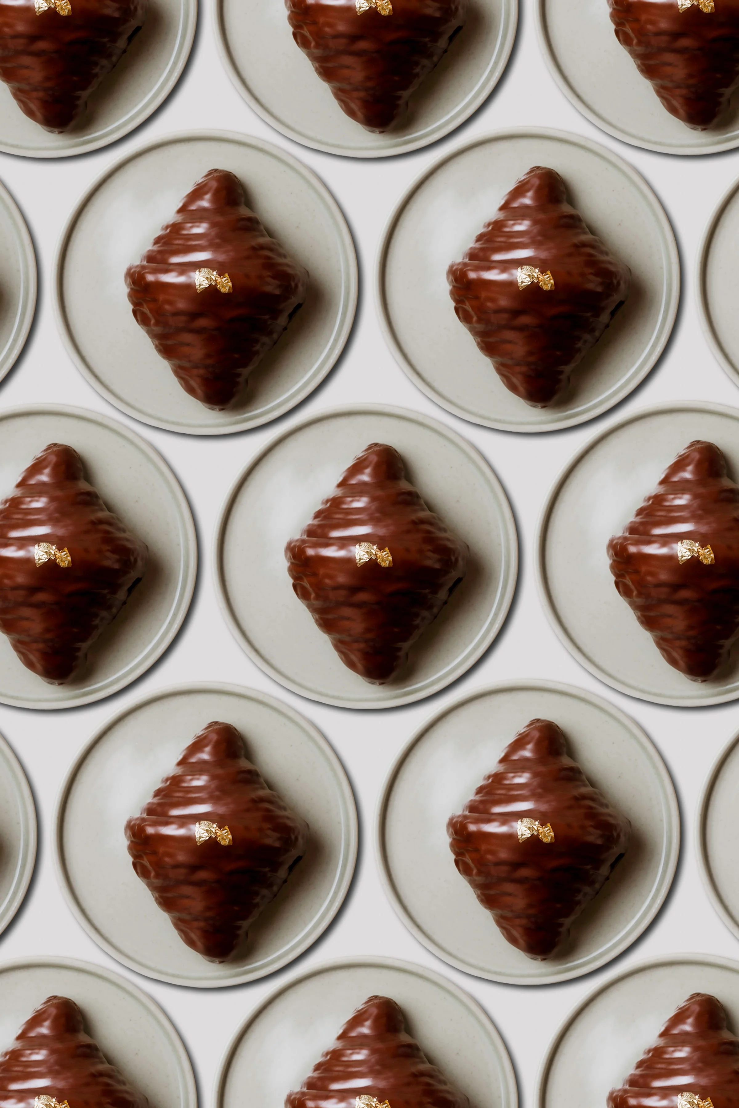 Croissants de chocolate en platos blancos dispuestos en una cuadrícula.