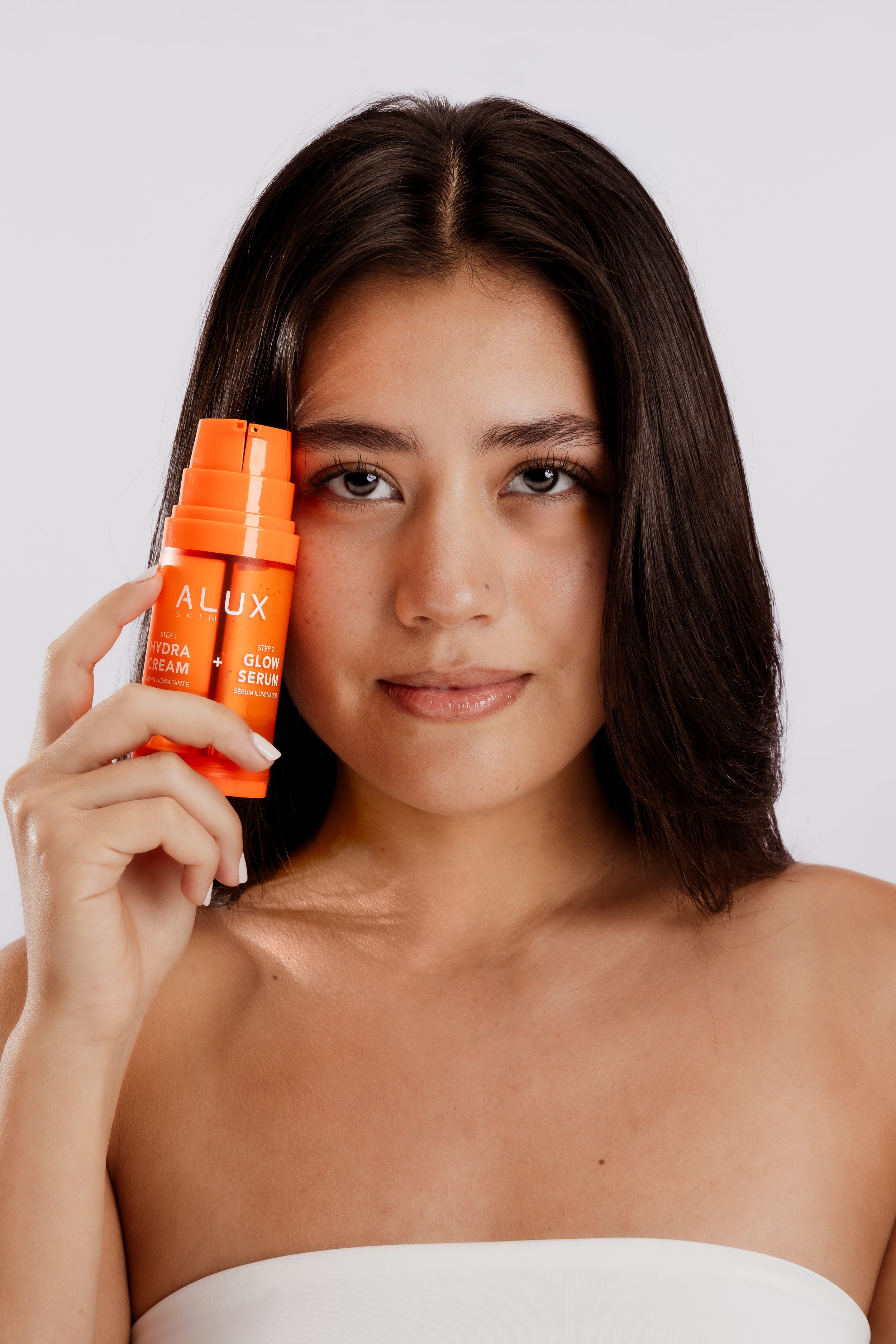 Modelo sosteniendo un producto de cuidado facial Alux.