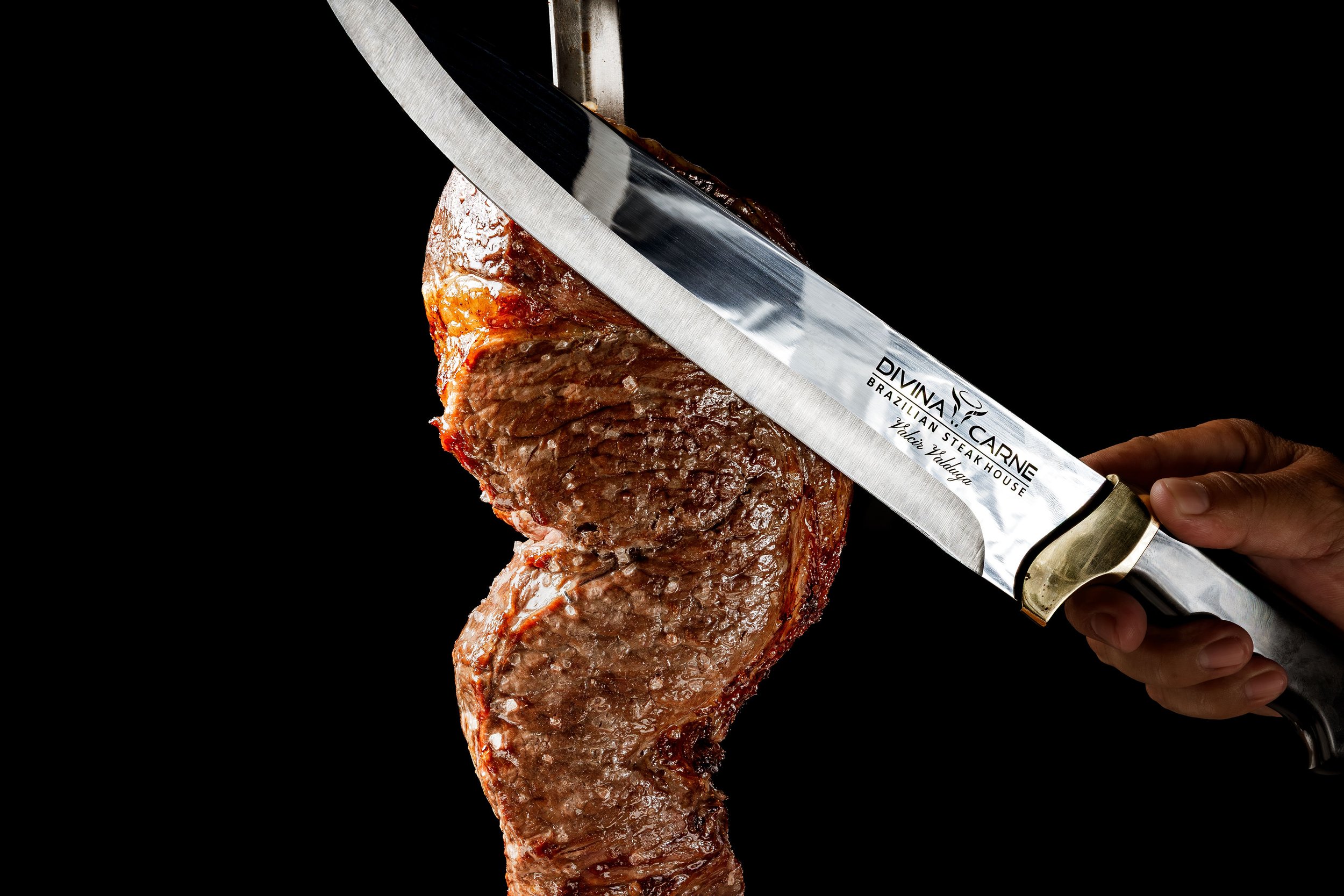 Mano cortando carne asada con un cuchillo.