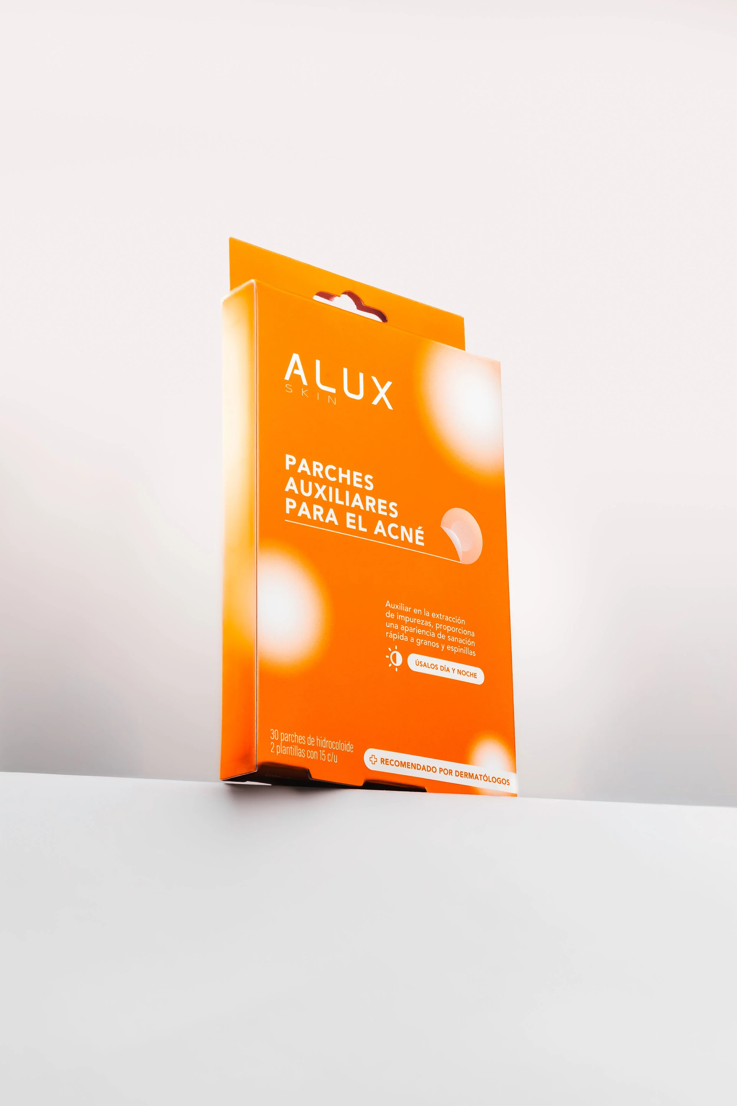 Caja naranja de parches para la piel Alux sobre fondo claro.