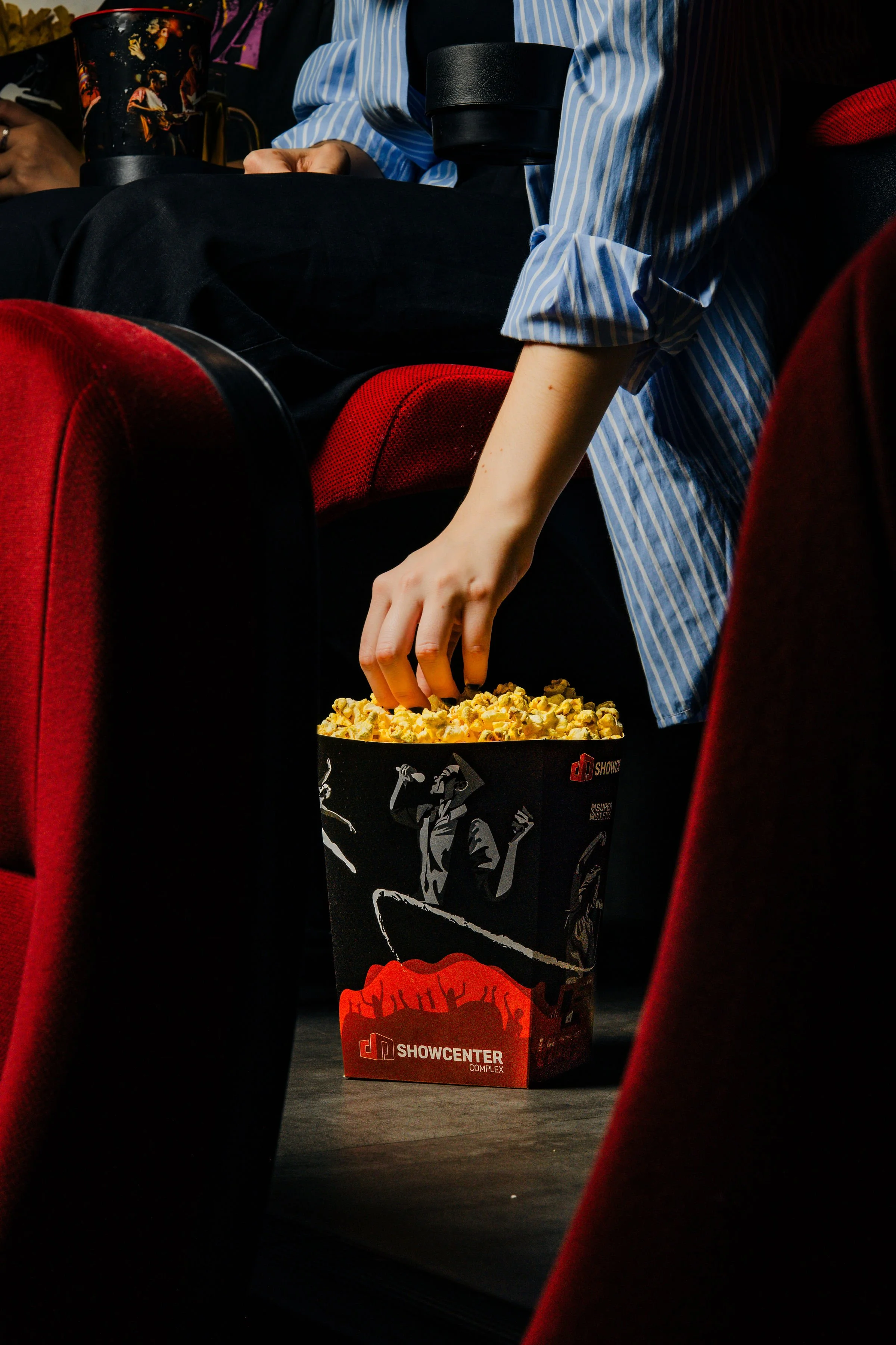 Persona tomando palomitas en una sala de cine.