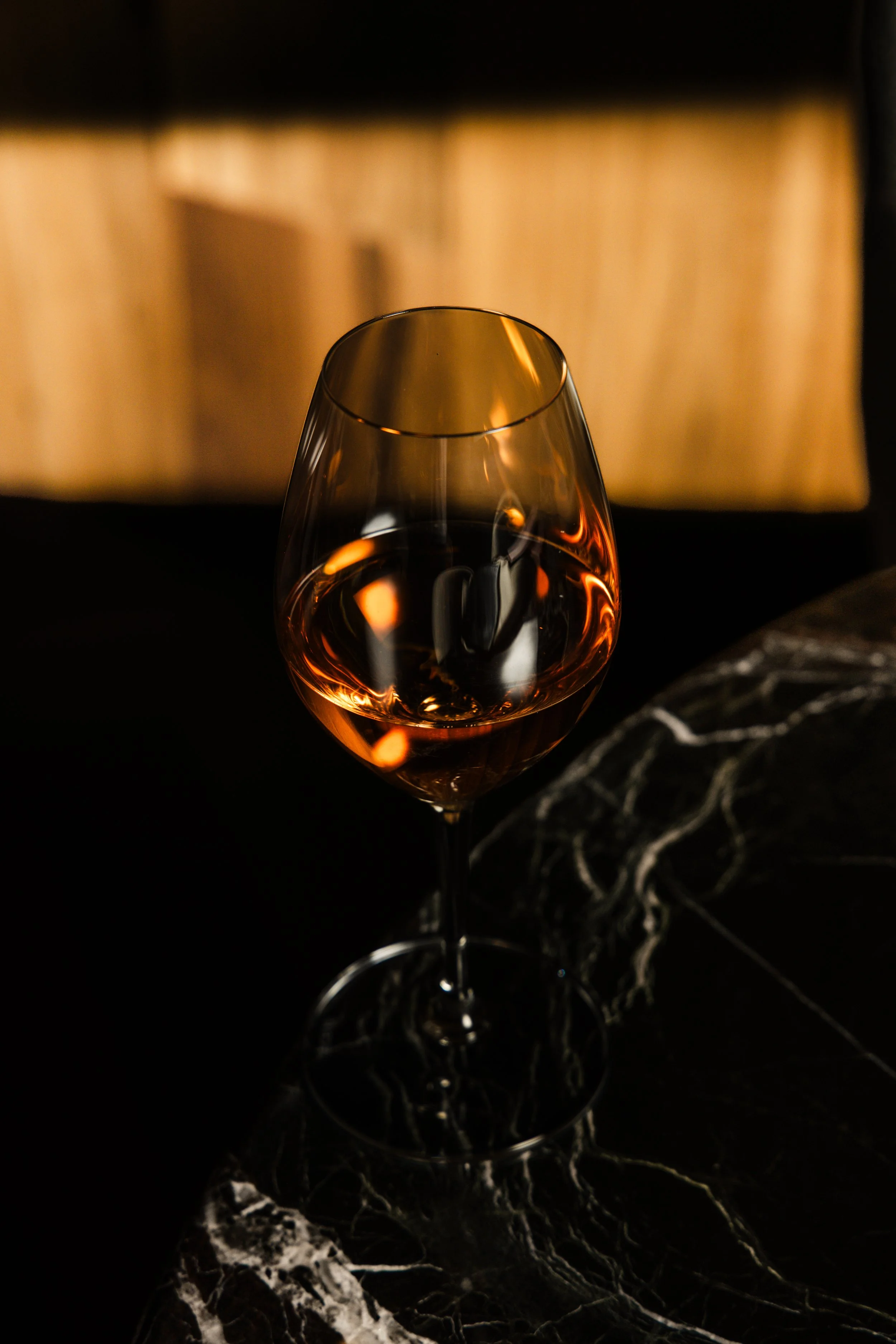 Copa de vino sobre una mesa de mármol oscuro.