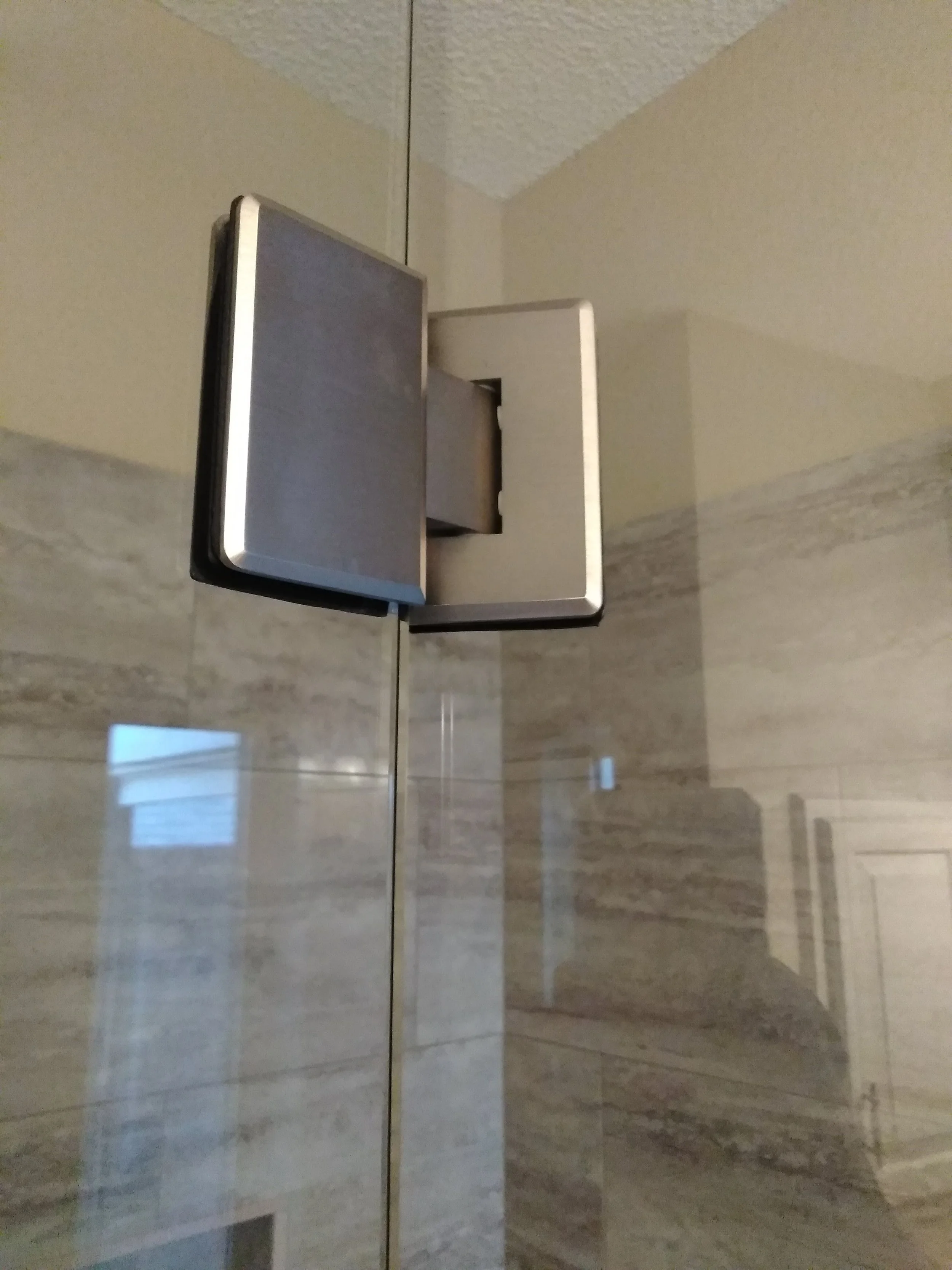 A bathroom mirror and sink with a beige tiled wall background.