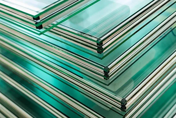 Stack of glass sheets with greenish tint and black corner protectors.