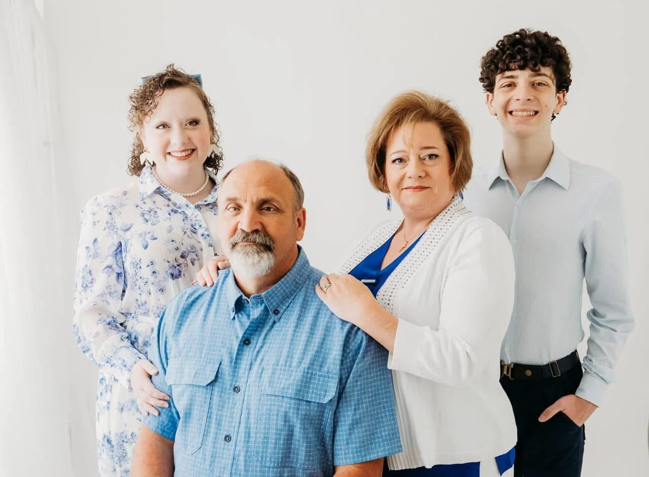 A family of five posing for a portrait in front of a plain white background.