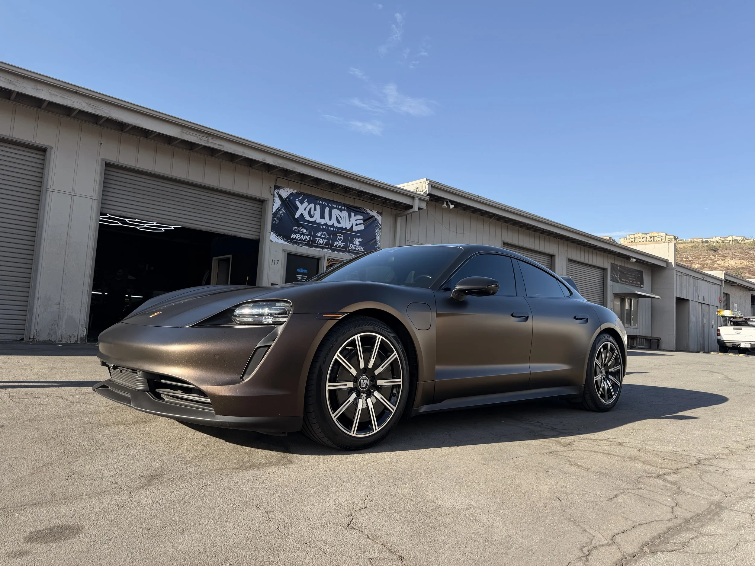 Matte bronze Porsche Taycan parked outside the Xclusive Auto Customz shop in Santee, CA
