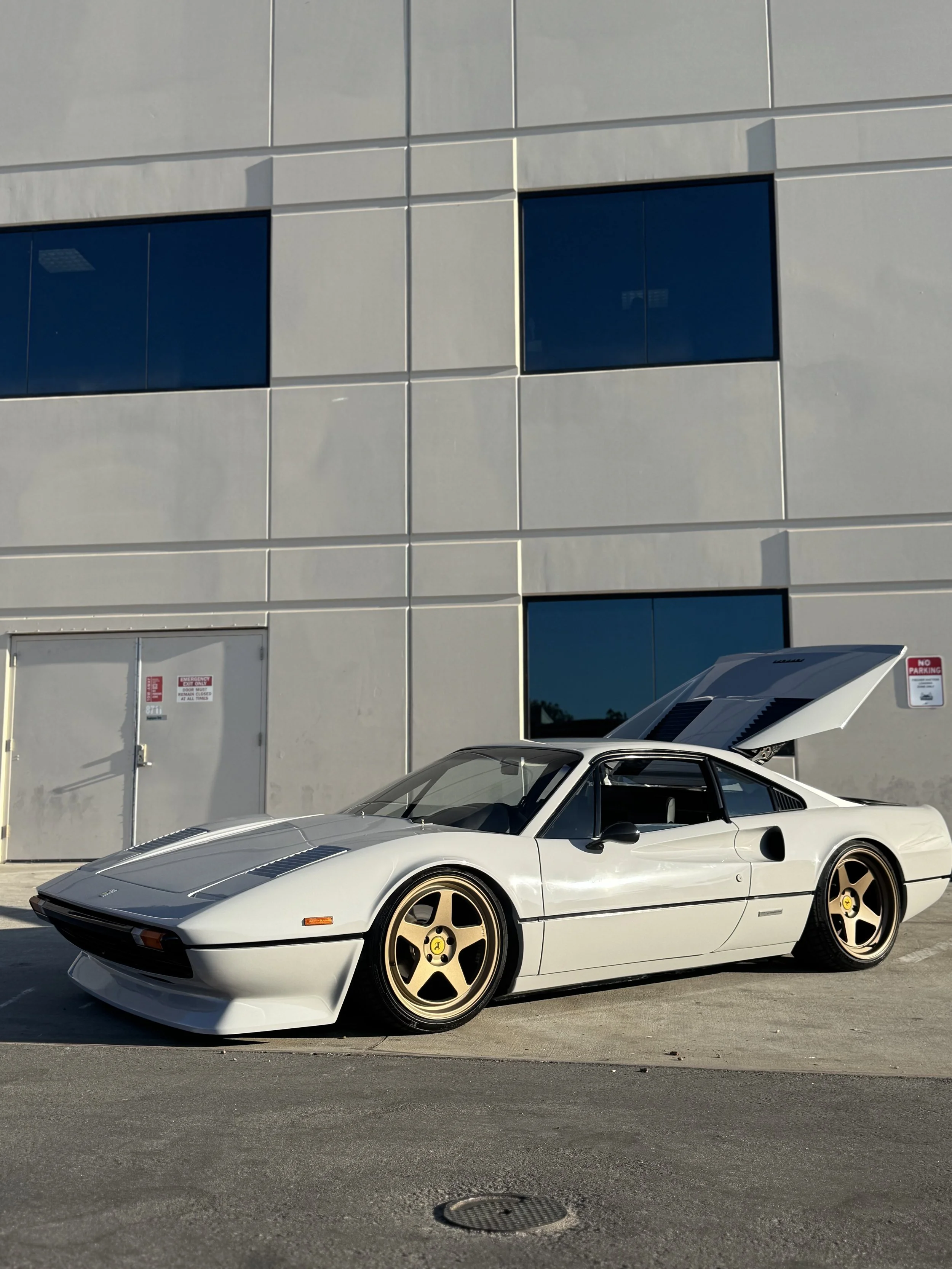 White classic Ferrari with gold wheels and open hood at Xclusive Auto Customz in Santee, CA