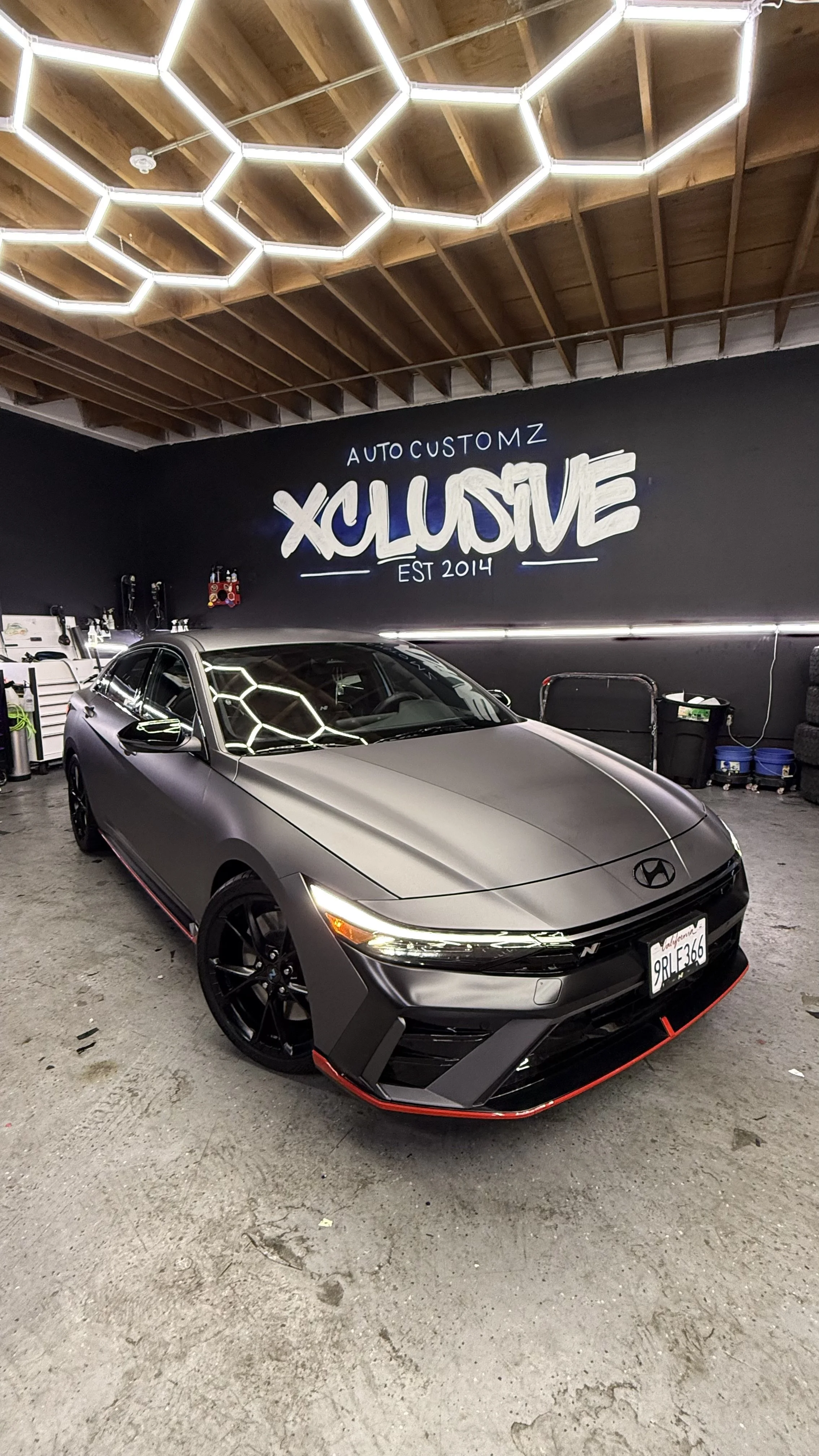 Matte gray Hyundai sedan with a vinyl wrap inside the Xclusive Auto Customz shop in Santee, CA