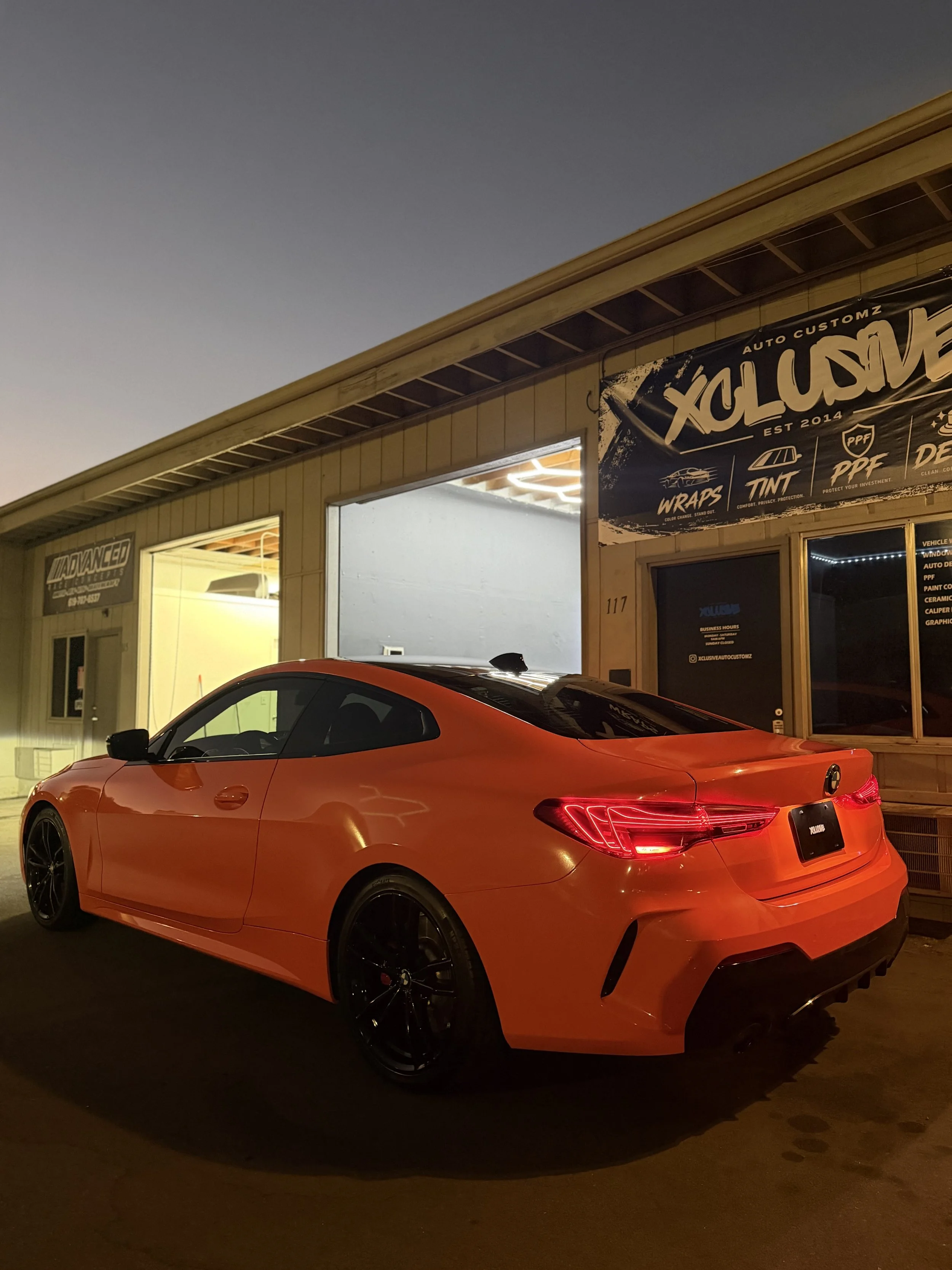 Orange BMW coupe rear view with custom vehicle wrap at Xclusive Auto Customz in Santee, CA