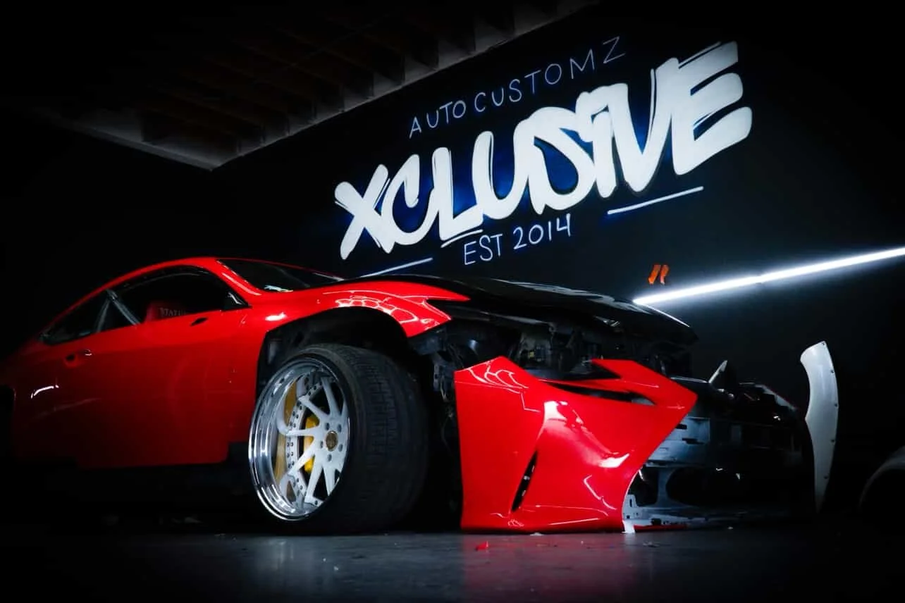 Red modified sports car in front of the Xclusive Auto Customz graffiti wall in Santee, CA