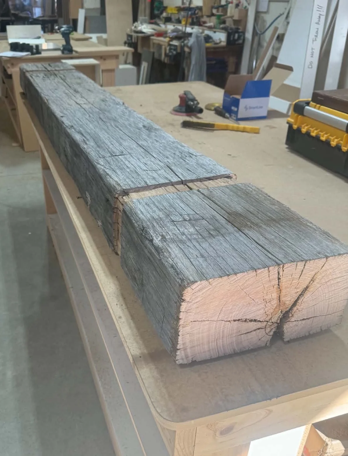 Large reclaimed Australian Eucalyptus hardwood beams on a workshop bench, ready for handcrafted furniture production by ORIGIN BY DESIGN.