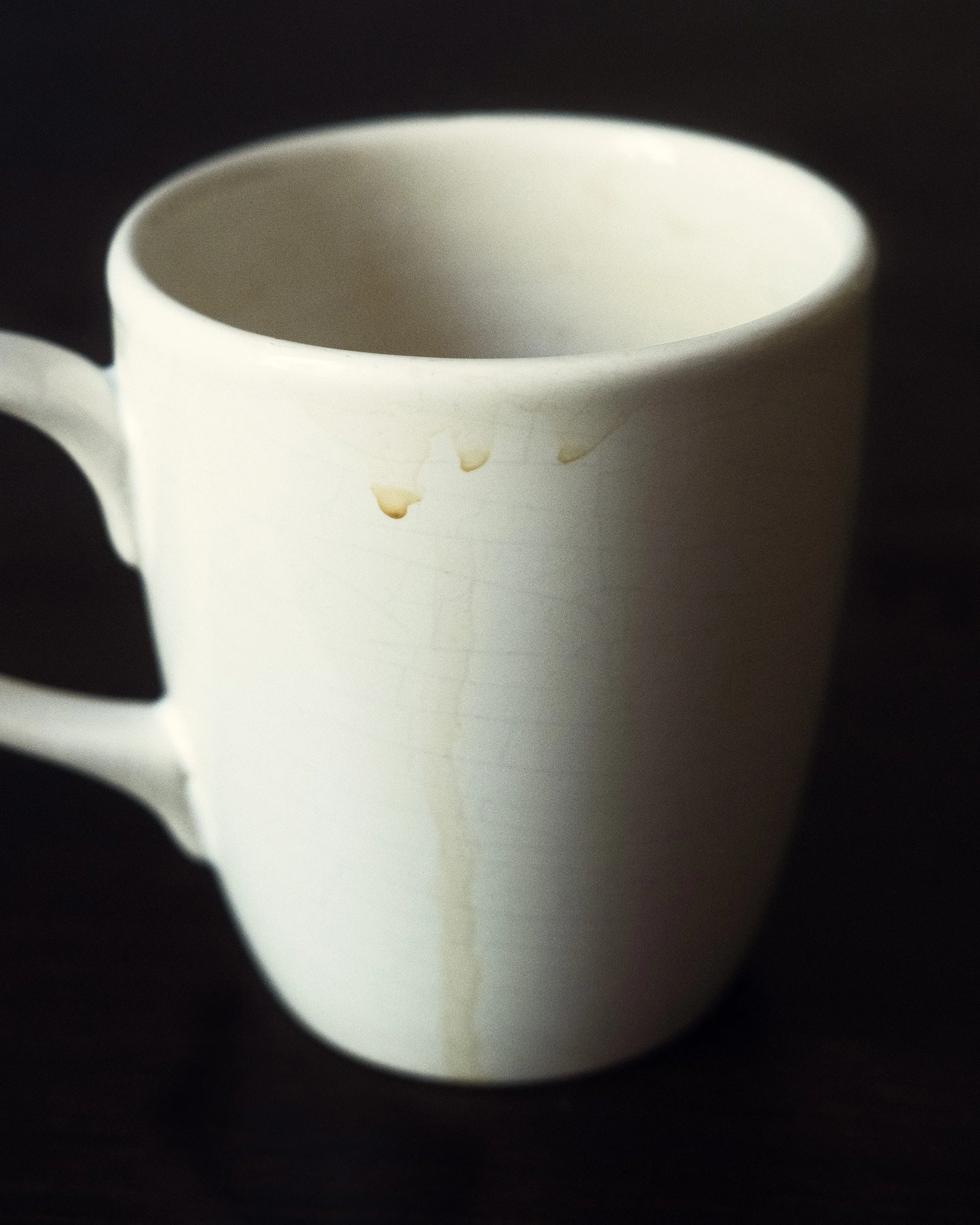 Close-up of a white ceramic mug against a dark background.