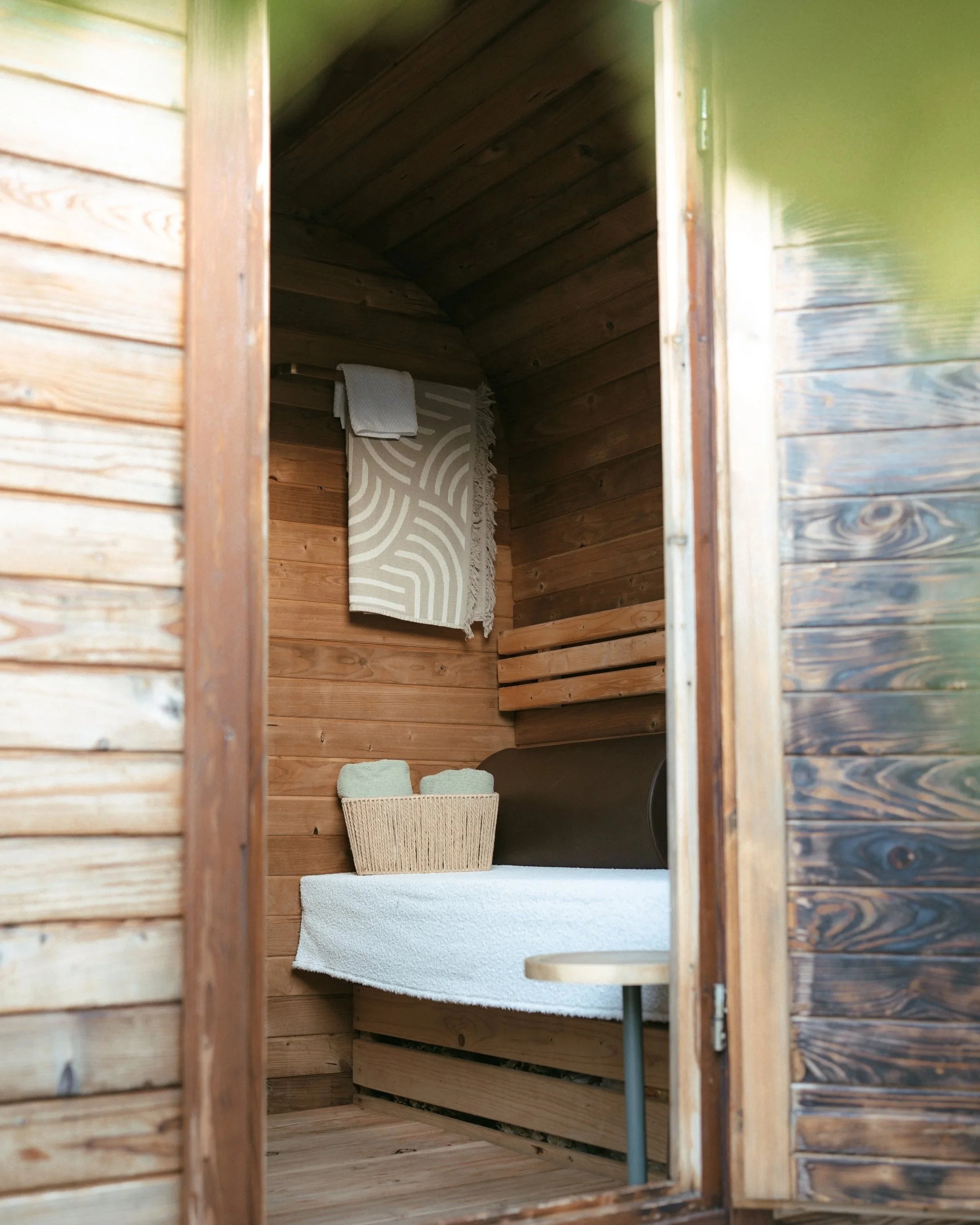 Innenraum einer kleinen Holzhütte, mit einem Handtuch und einem Korb auf einem gesteppten Holzstuhl.