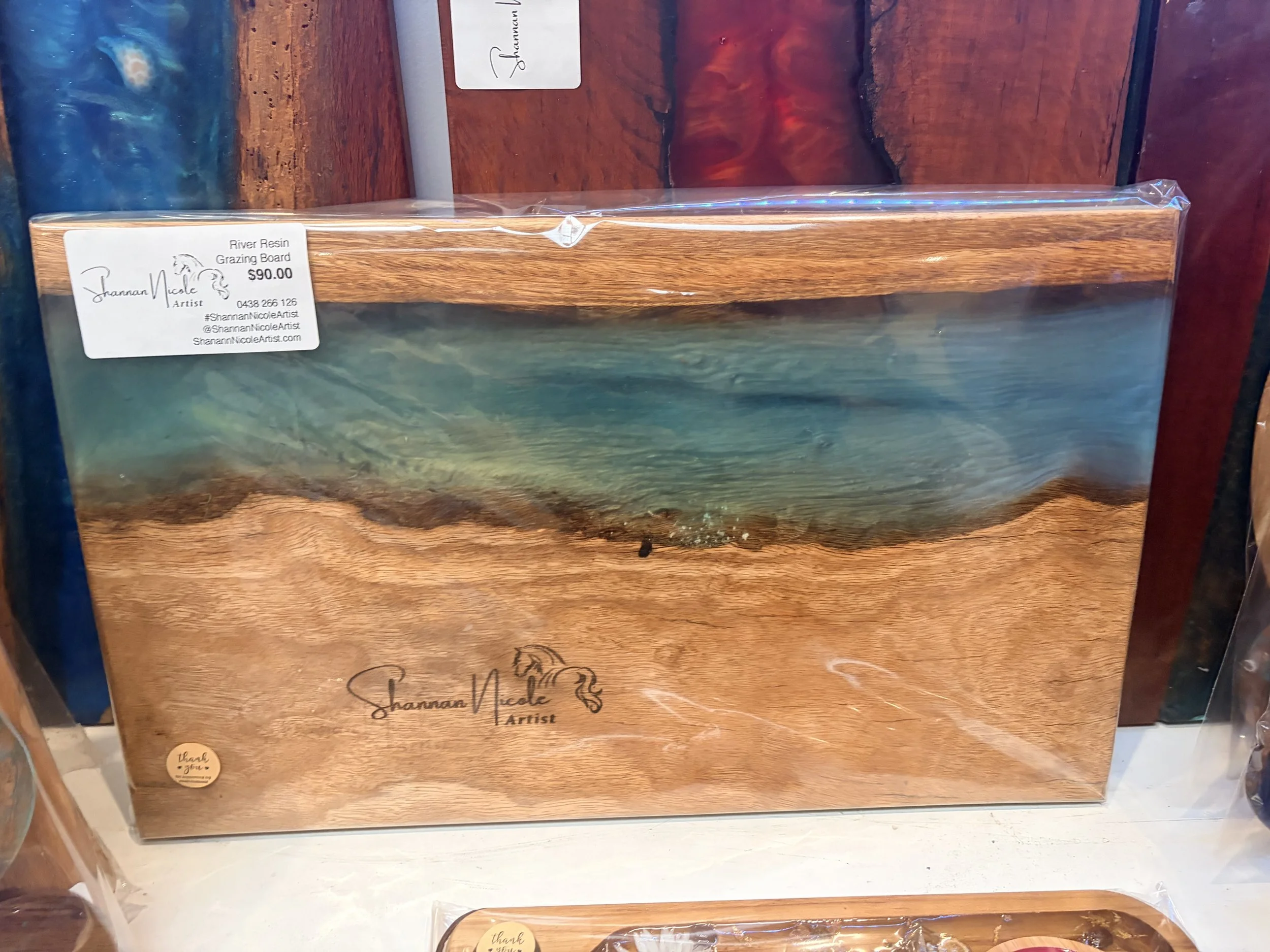 Wooden resin grazing board with a label indicating it costs $90, displayed on a shelf in a store.