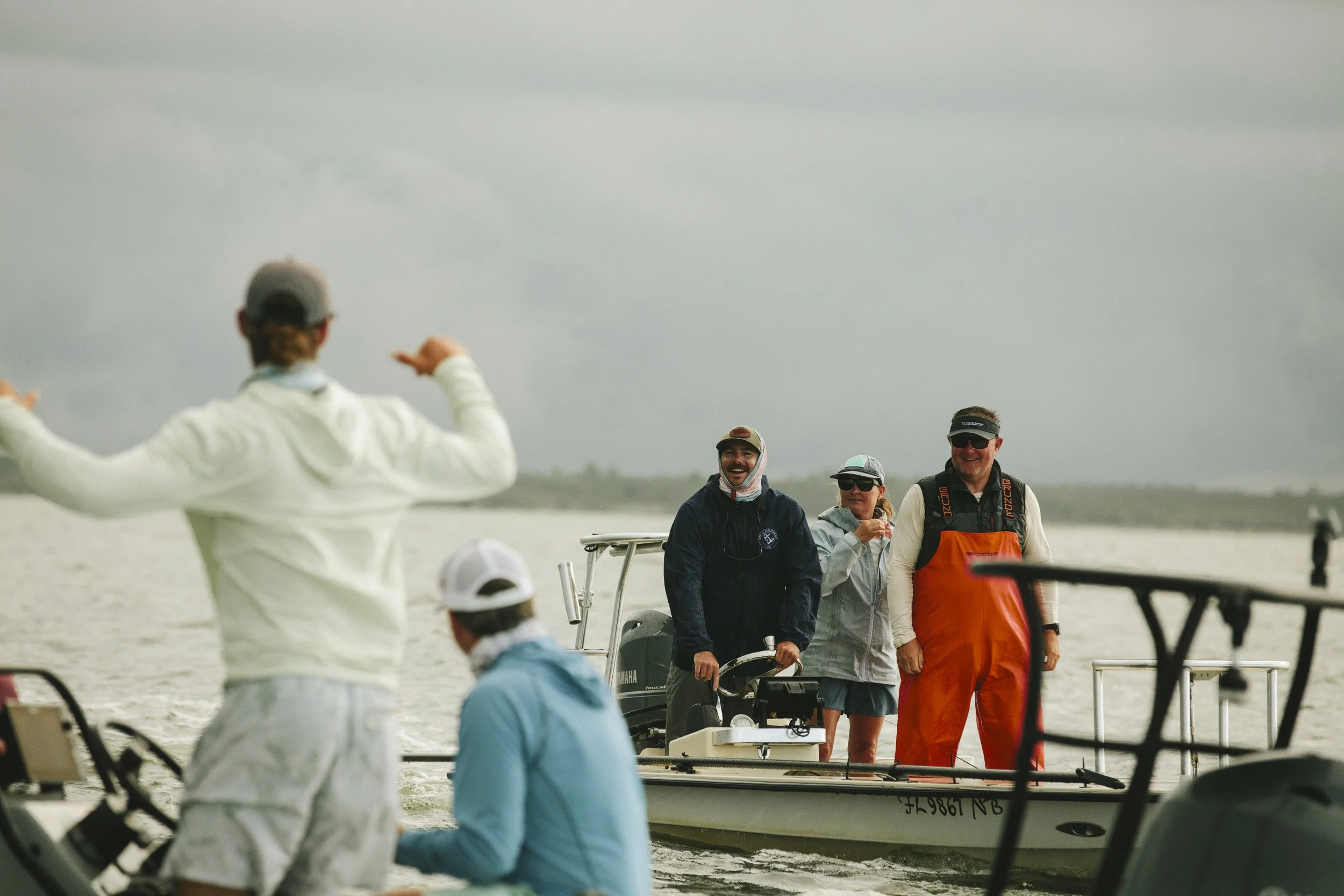 People on a boat preparing to set out on a cloudy day, with some standing on the boat and others onboard.