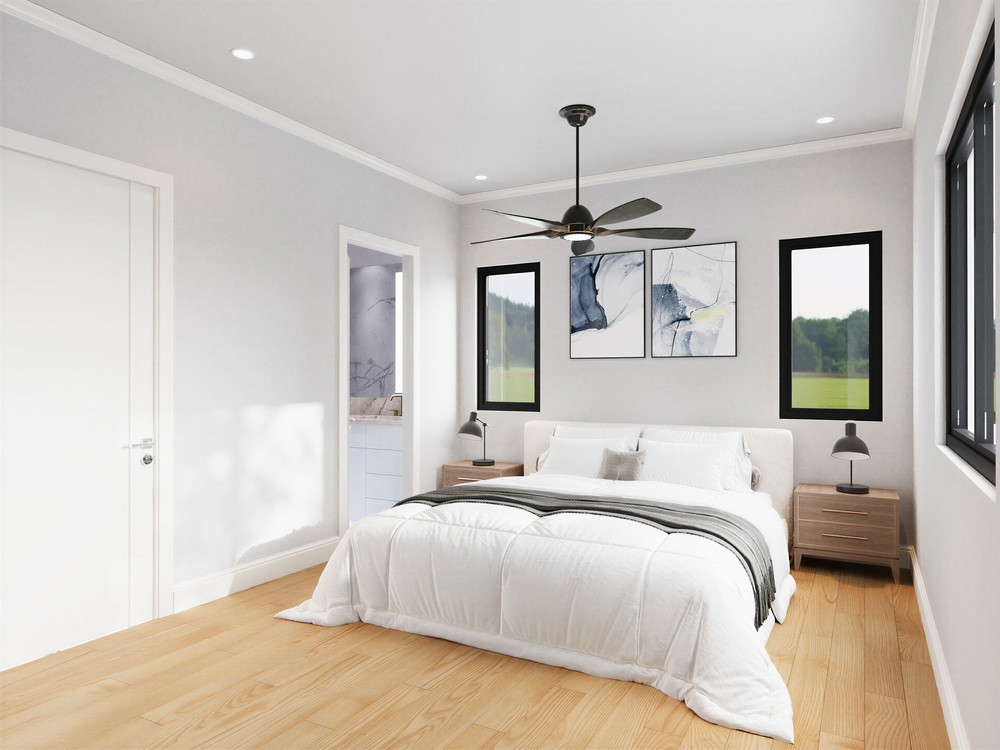 A modern bedroom with a white bed, two wooden nightstands, black wall art, and a ceiling fan with dark blades. Large windows show a green outdoor view.