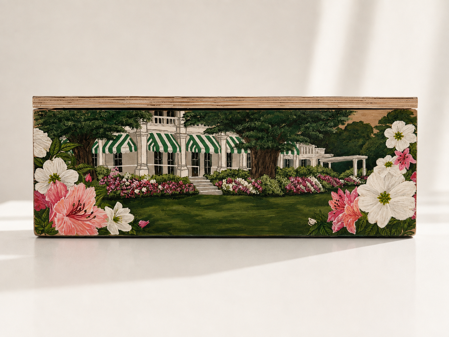 Decorative rectangular wooden box featuring a landscaped scene of a white house with striped green and white awnings, surrounded by colorful flowers and trees.