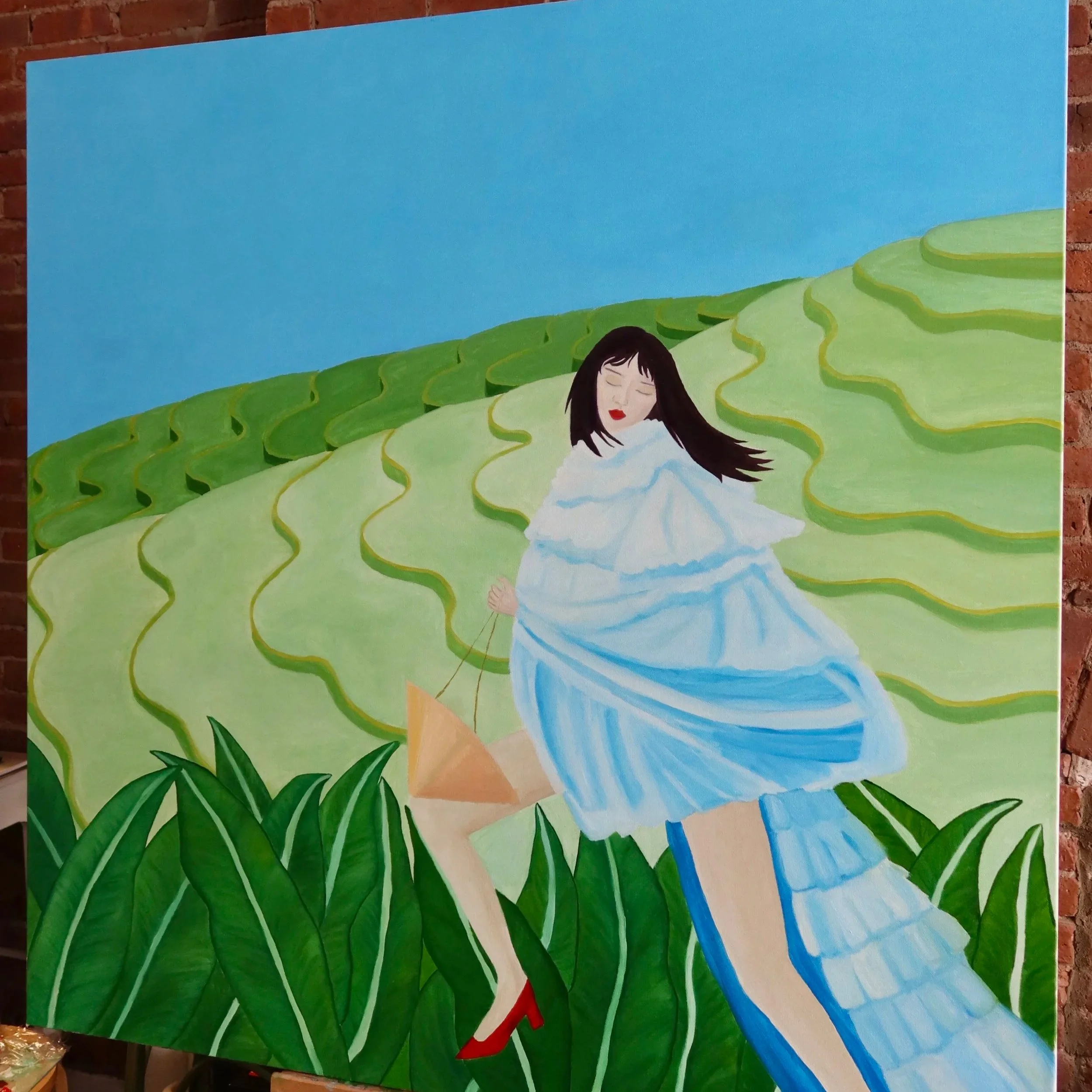 A painting of a woman with long dark hair and red shoes walking through a lush green field with a bright blue sky and flowing water nearby.