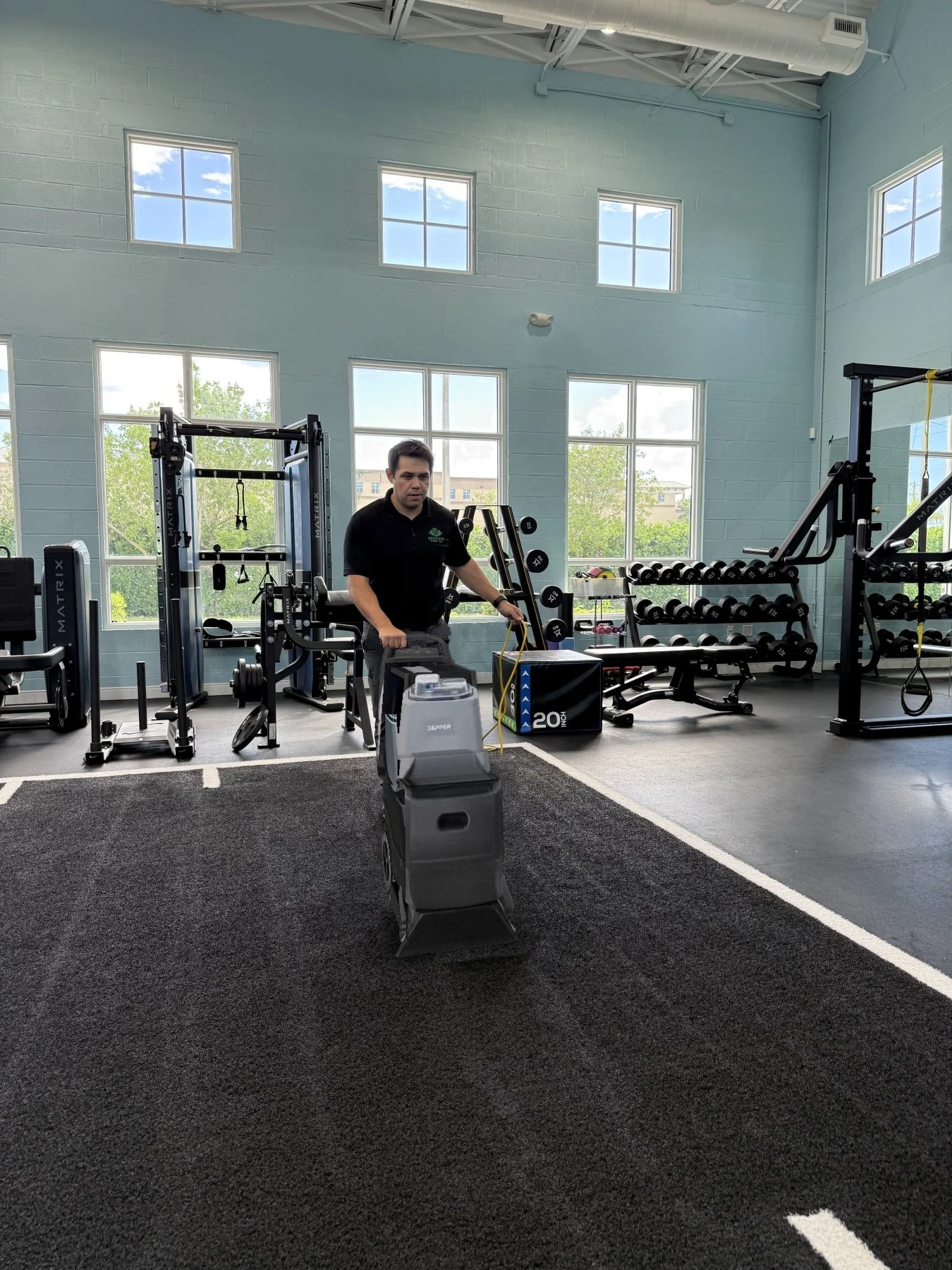 Technician cleaning artificial turf in a gym