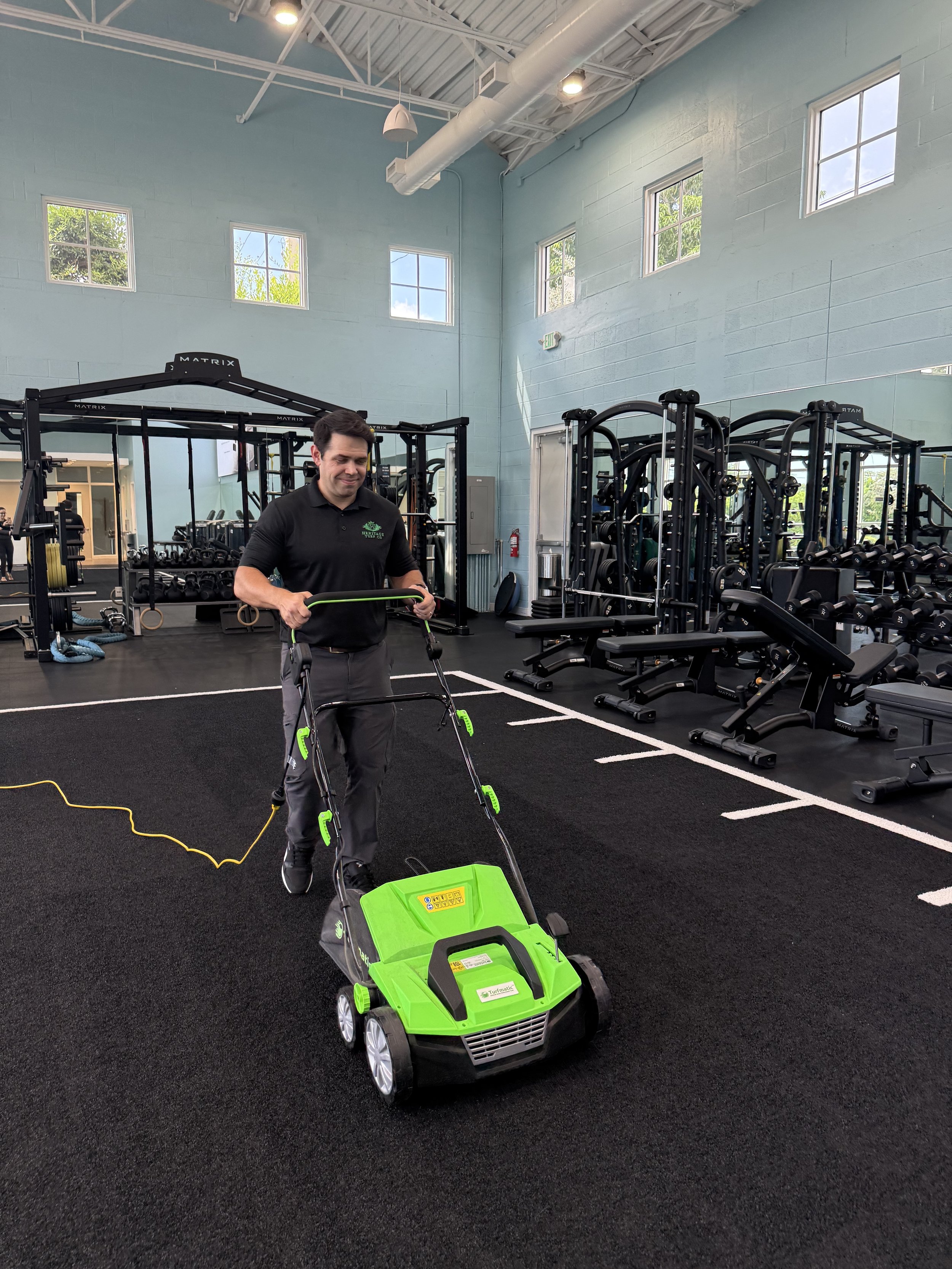 Technician power brushing and cleaning artificial turf in a commercial gym