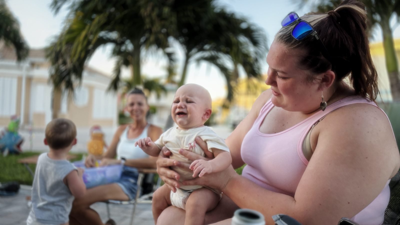 Morgan holding baby Koby while the family sits outside together