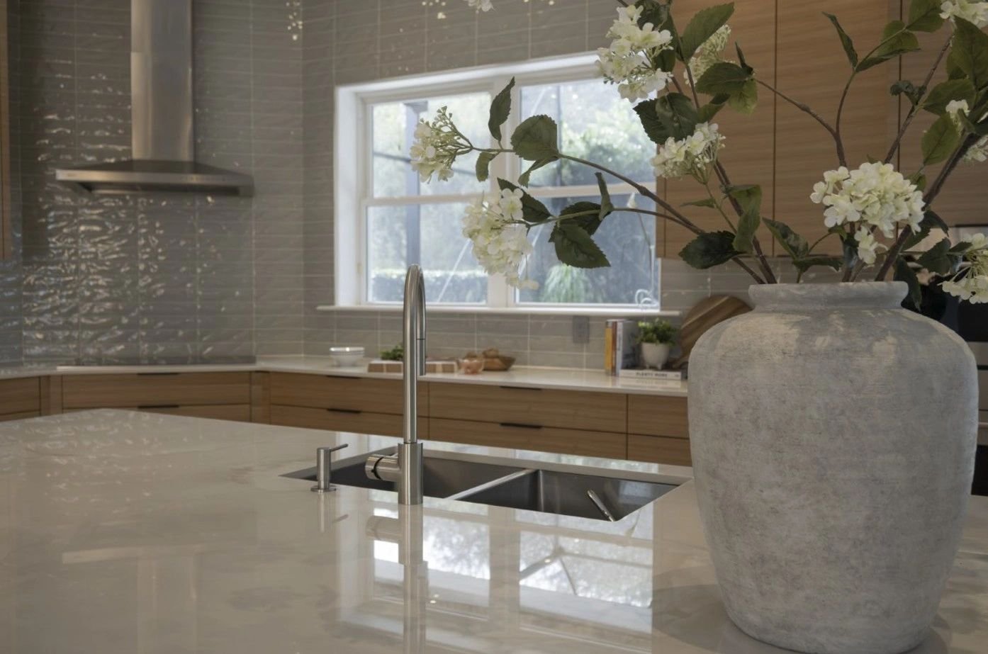 Modern kitchen with marble countertop and large flower vase.