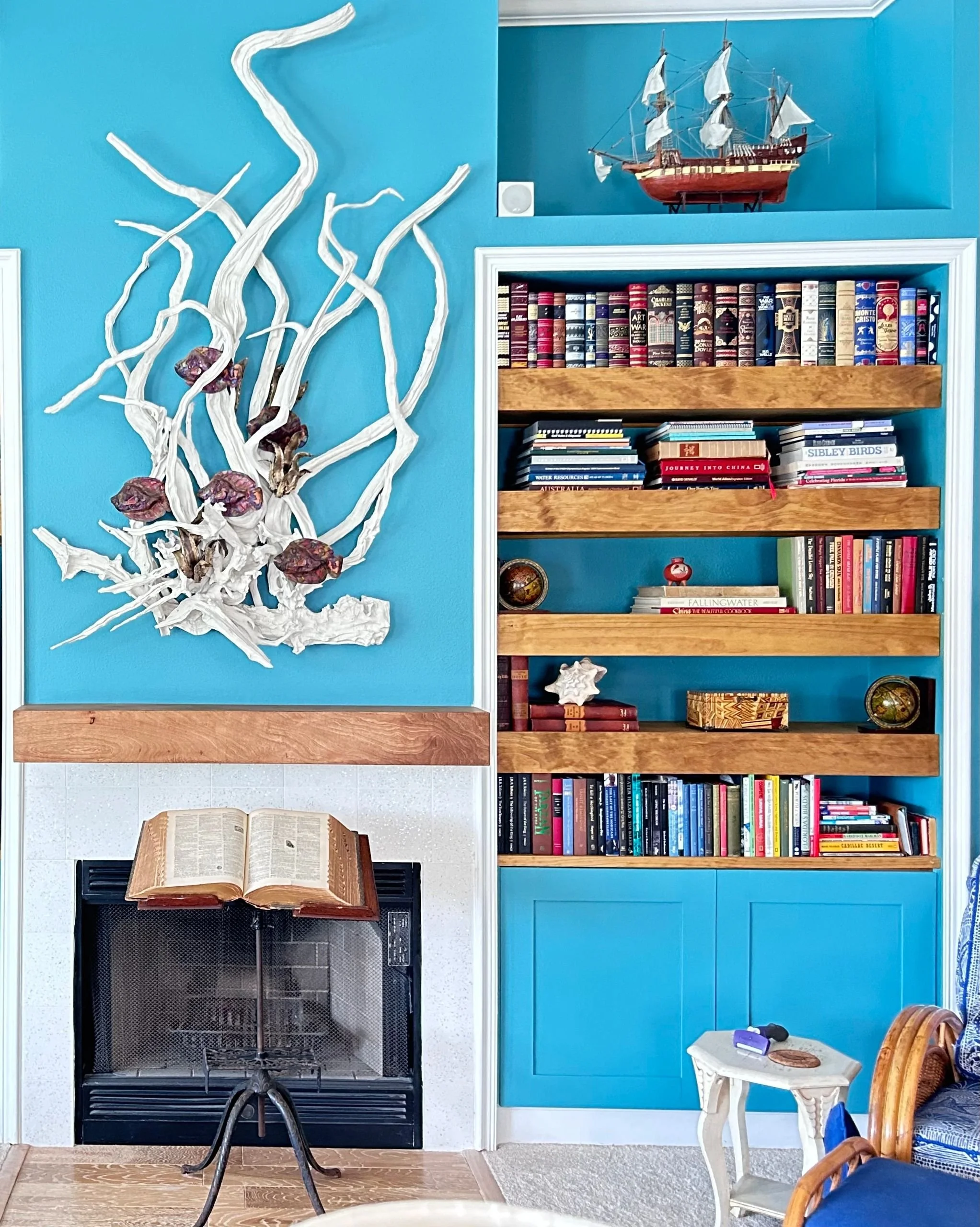 Styled shelves with coral accents and books by AW Better Home Spaces