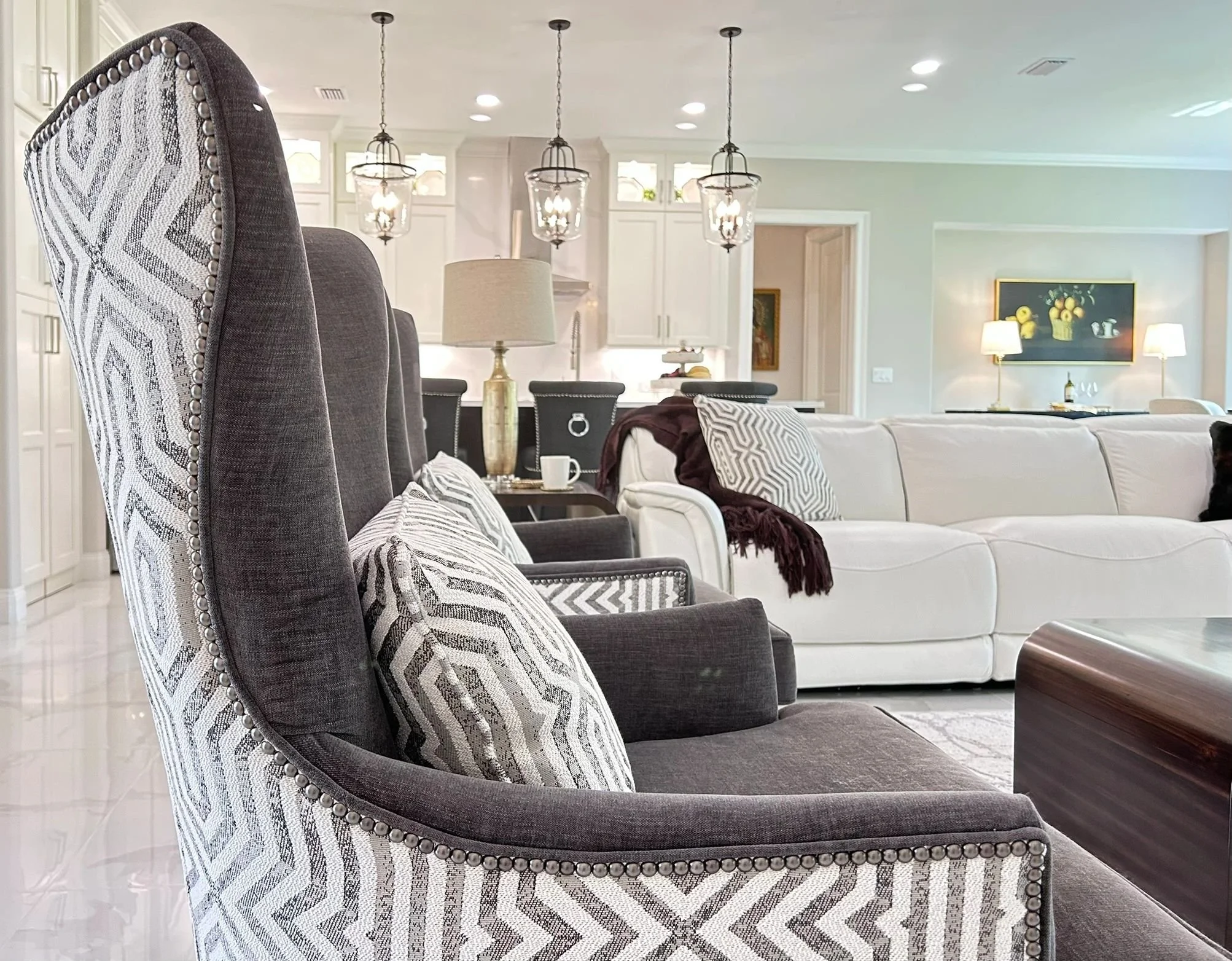 Modern living room with patterned armchairs and white sofa under warm lighting.