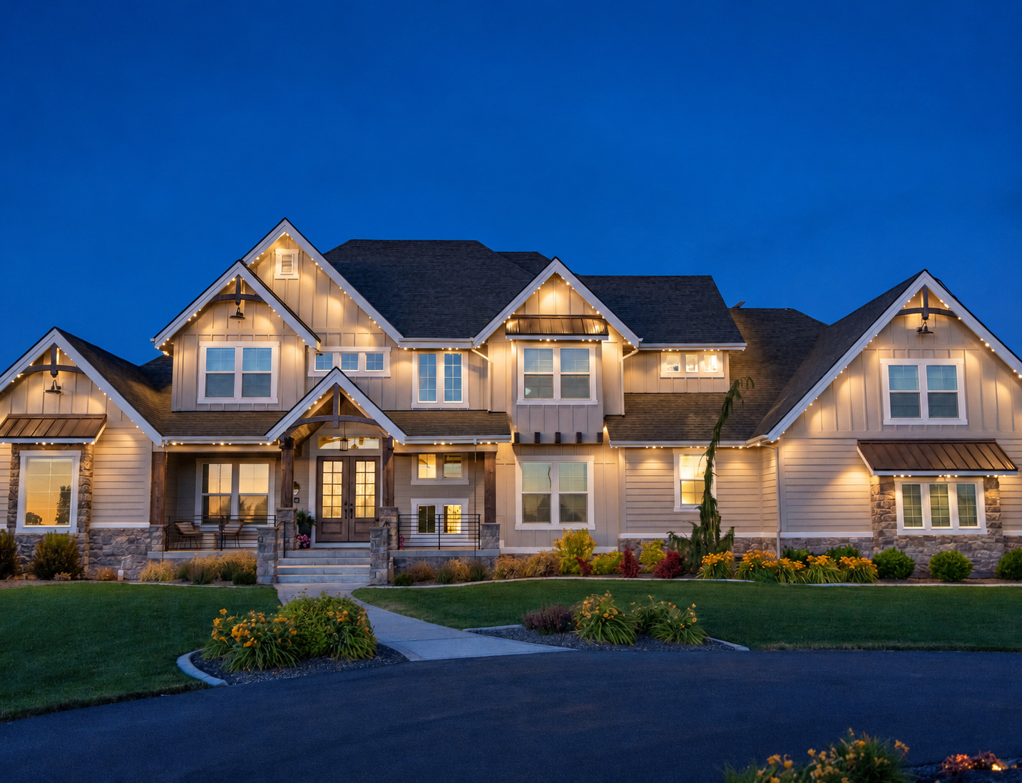 Warm white permanent lights trace the gables and porch of a two-story gray-sided home at dusk.