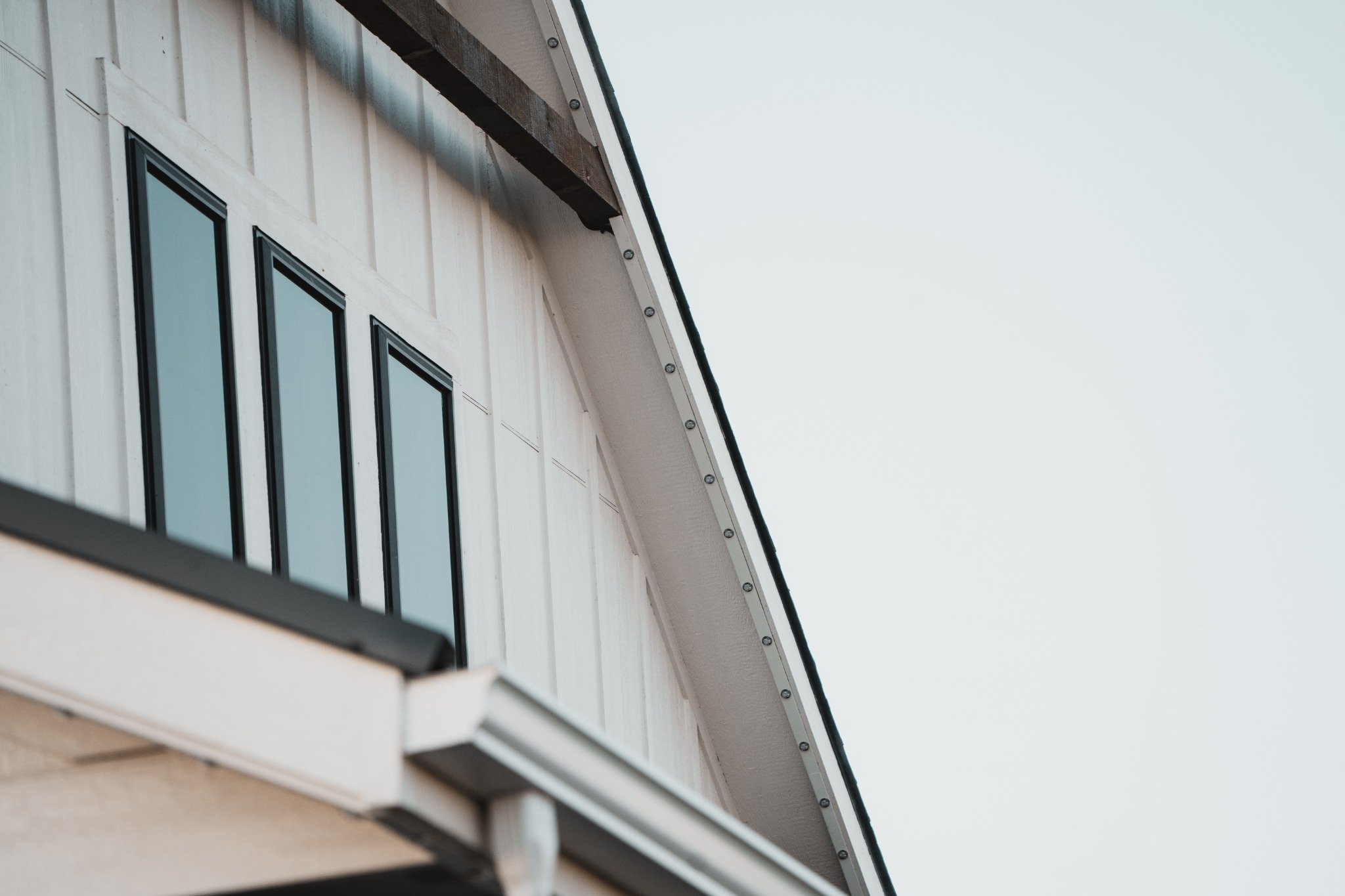Daytime close-up of permanent lights recessed into a slim, color-matched aluminum channel beneath a home’s gable.