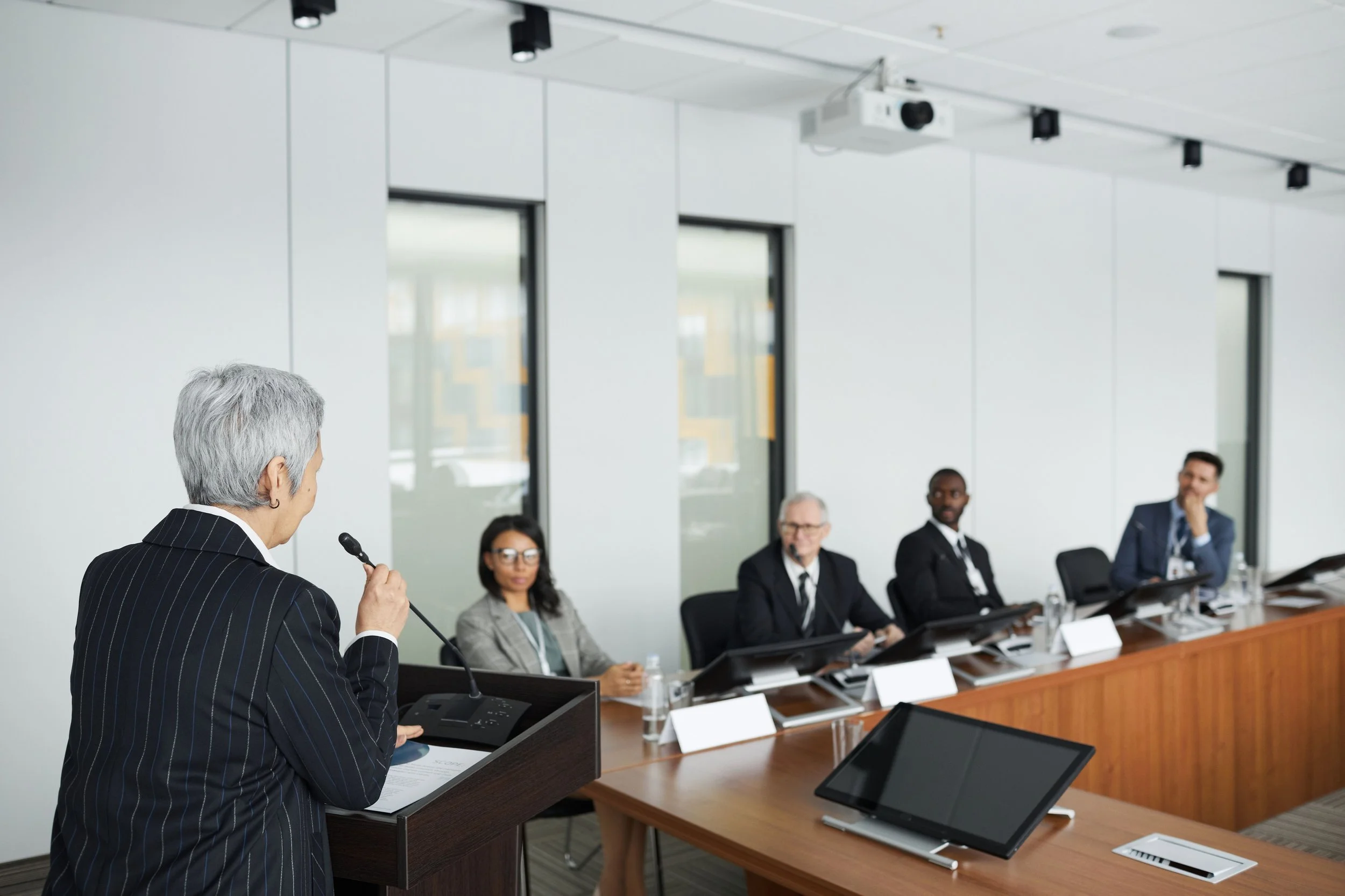 Businesswoman speaking at a conference table with a diverse panel of professionals