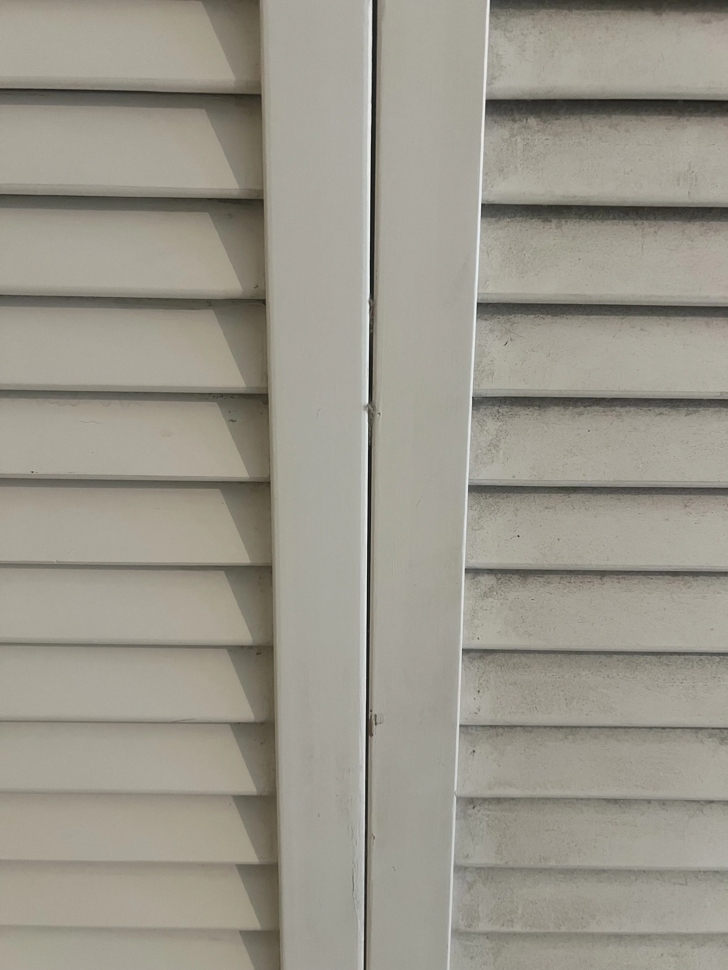Close-up of a window with white horizontal blinds, showing slight dirt and dust buildup on the slats.