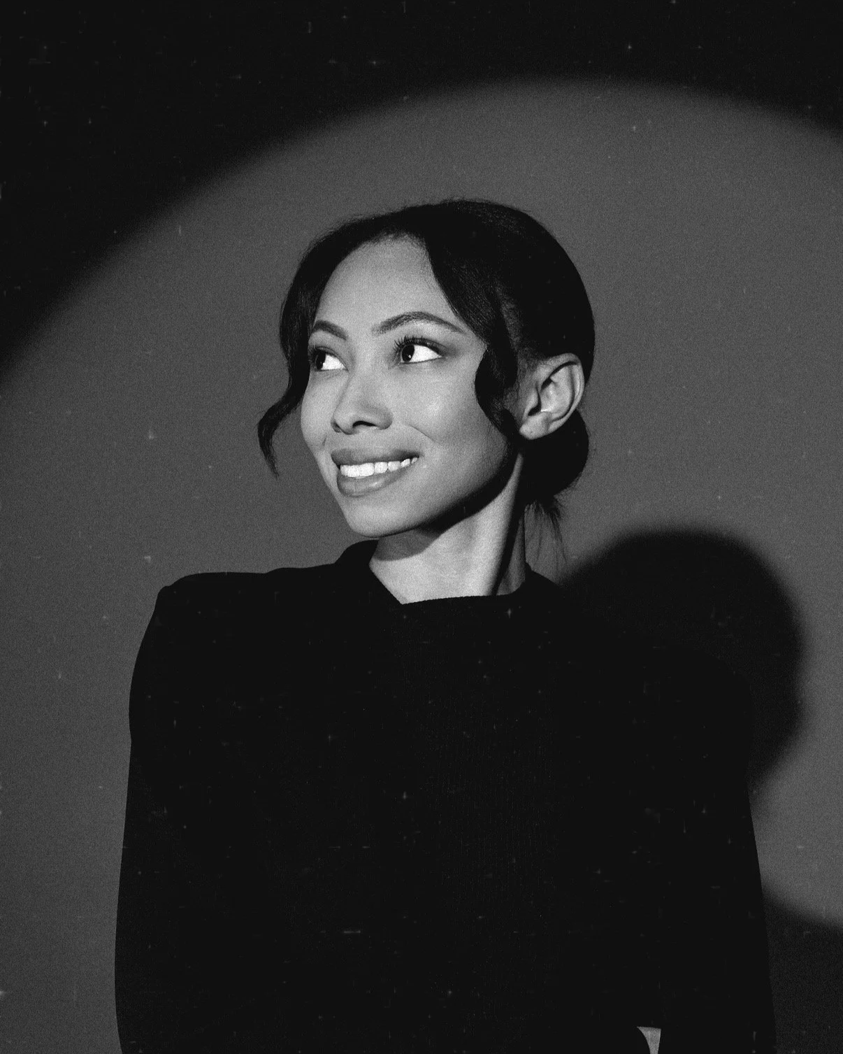 Black-and-white portrait of Bree Stephens with dark hair in a bun, wearing a black top.