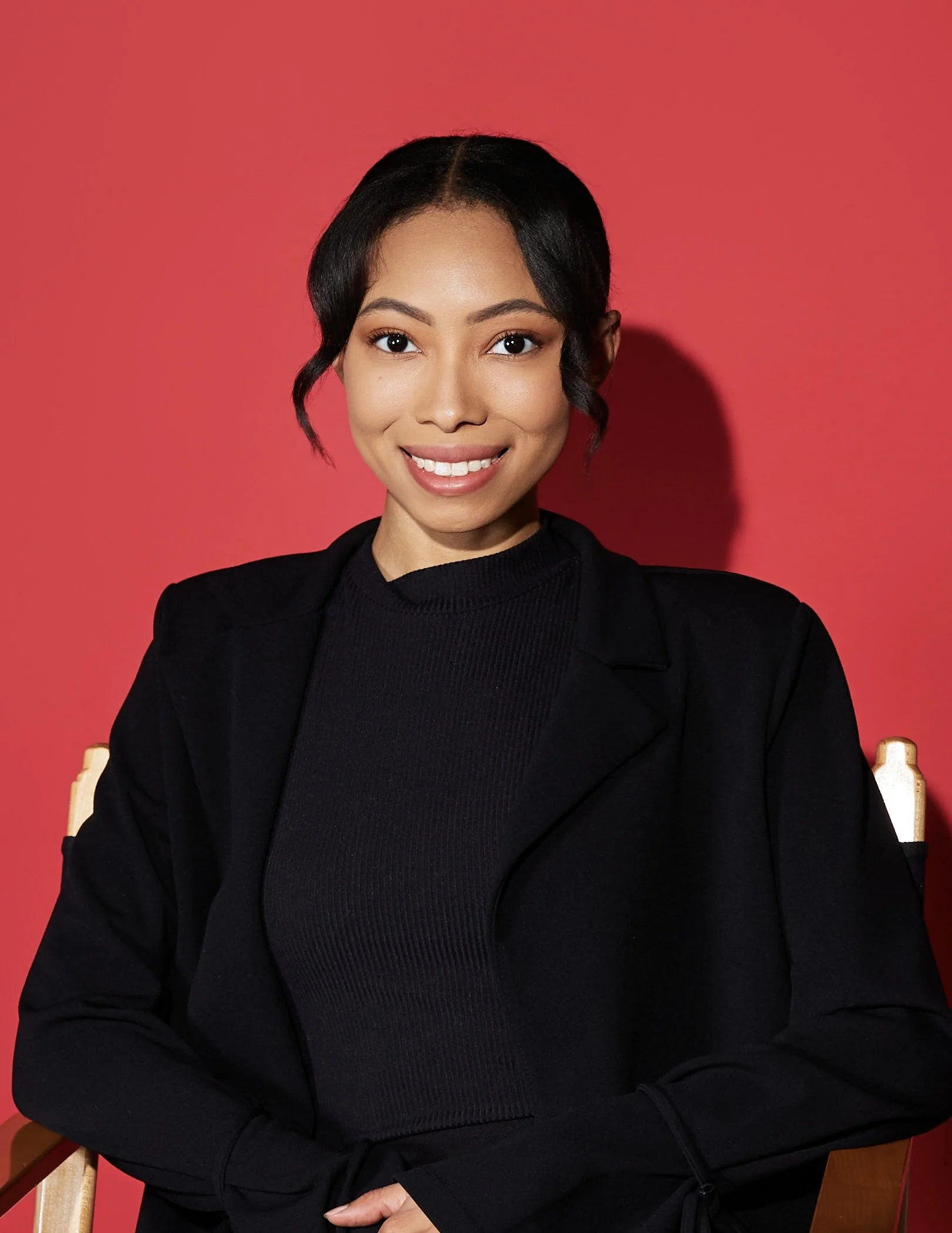 Bree Stephens smiling in black clothing seated against a red background