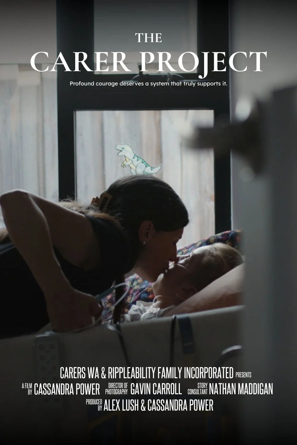Film poster titled "The Carer Project" showing a woman leaning over a young patient in a hospital bed, with a window in the background featuring a dinosaur sticker.