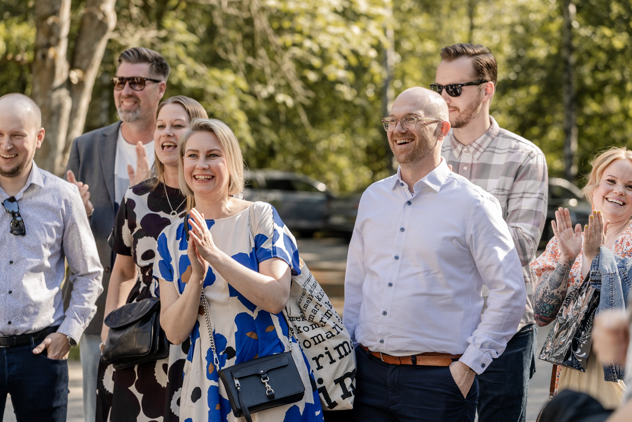 Iloinen ihmisryhmä nauramassa ja taputtamassa puistossa